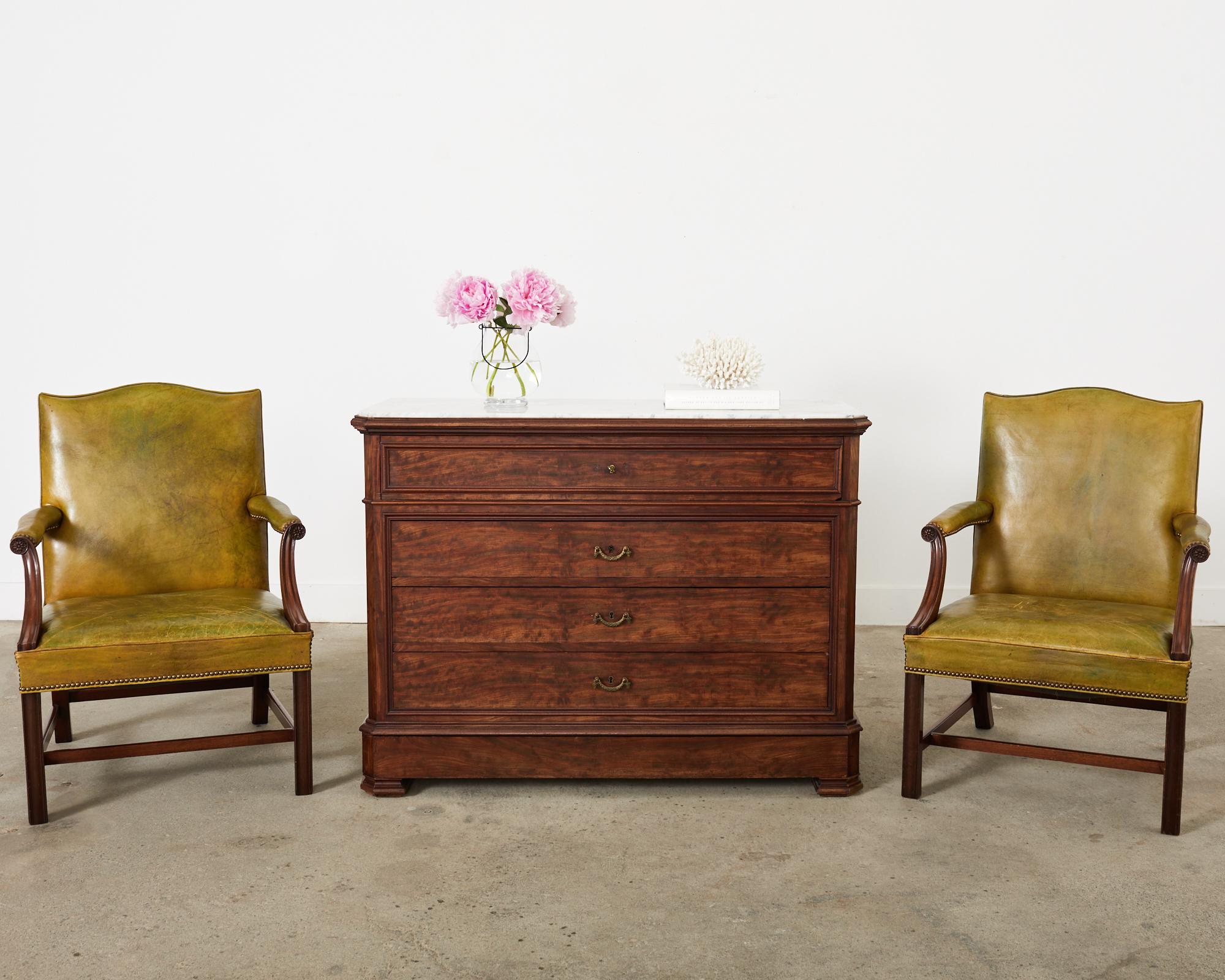 Extraordinary pair of 19th century English Georgian style mahogany Gainsborough library armchairs. The chairs feature full sized mahogany frames having a classic flat back with a serpentine crest and peaked corners. The generous seat has wide padded