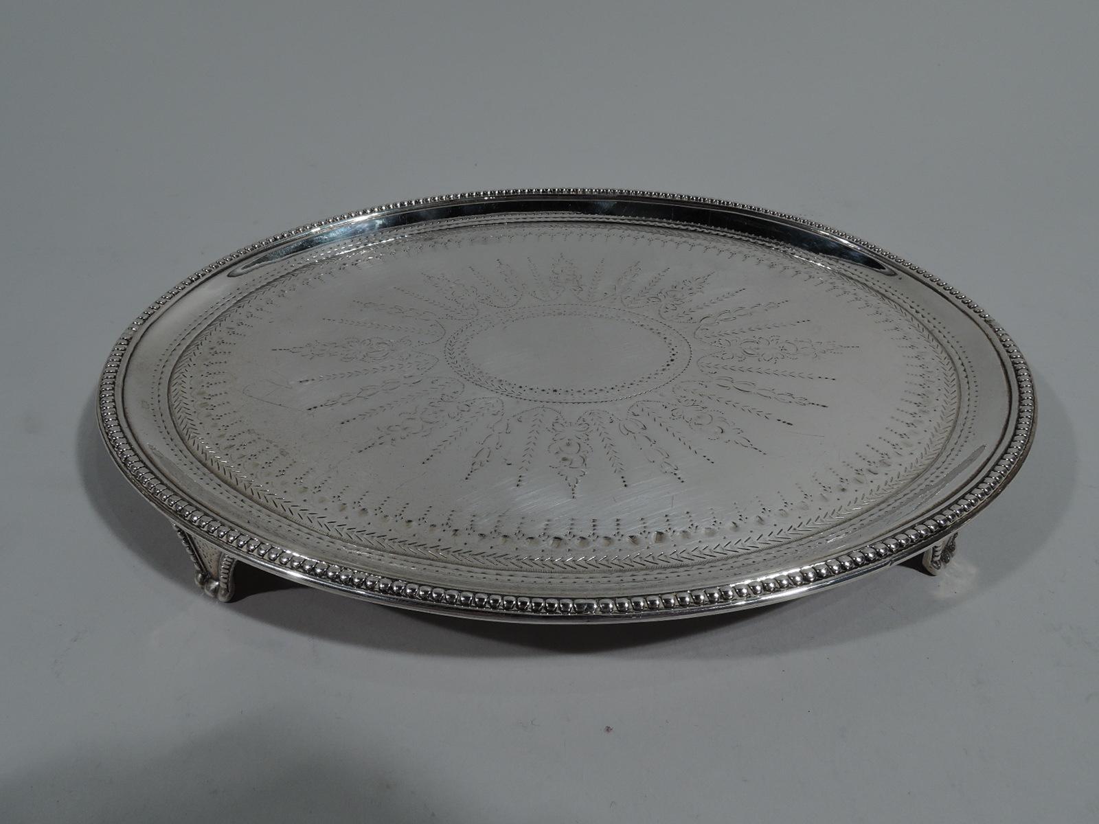 Pair of George III sterling silver salvers. Made by Elizabeth Jones in London in 1784. Each: Oval with beeded rim and 4 beaded triangular supports. Neoclassical ornament including large central patera (vacant) engraved on well. Supports same. Fully