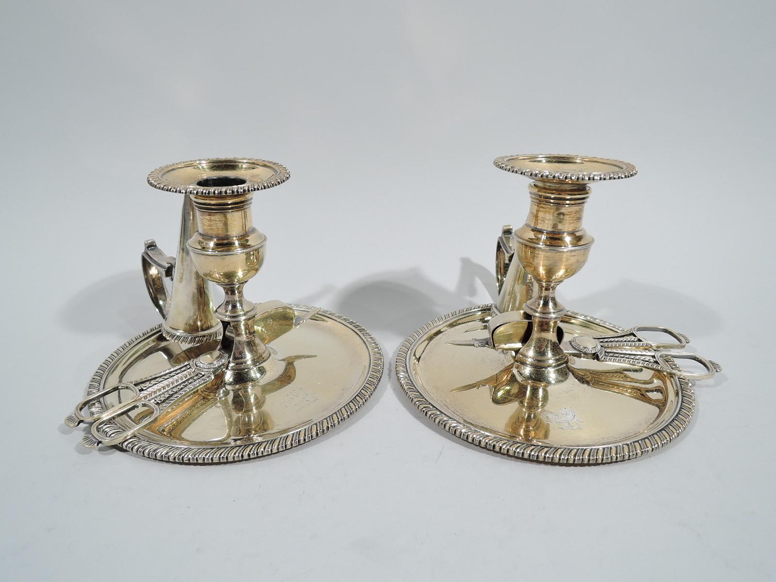 Pair of George III gilt sterling silver chambersticks. Made by Thomas & George Hayter in London in 1819. Each: Campana socket on spool foot mounted to open base inset with wick cutters. Round wax pan with capped flying scroll handle holding conical