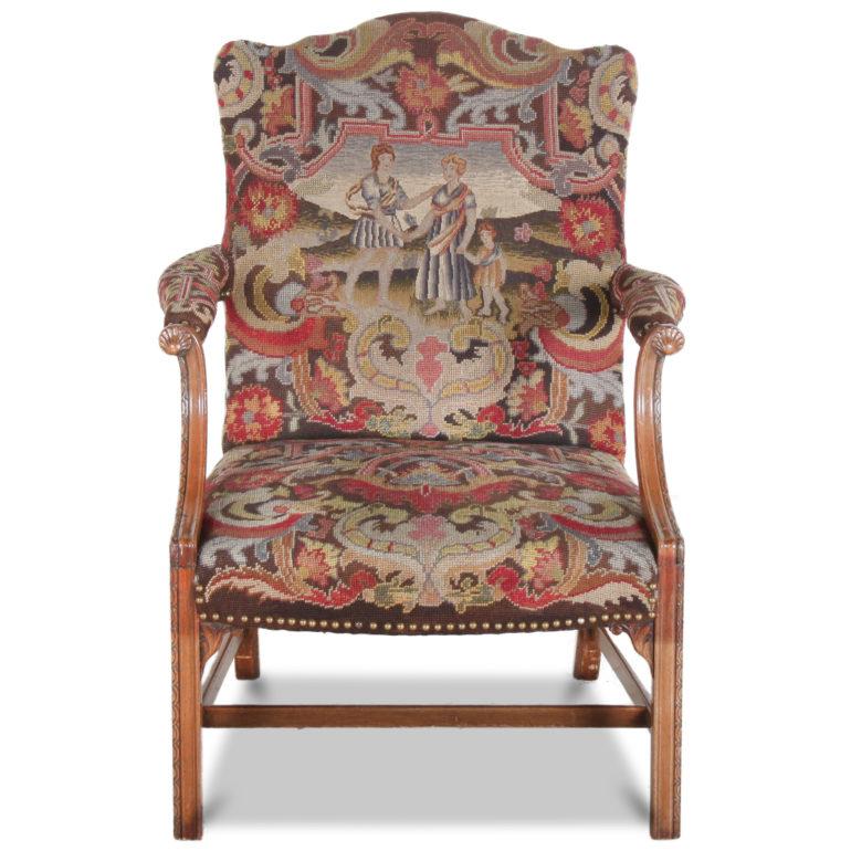 A pair of English mahogany framed Georgian style ‘Gainsborough’ armchairs or bergeres with needlework seats, backs and arms. Carved details to the arms and chair legs and metal stud accents to the edges of the upholstery.
Upholstery is in good