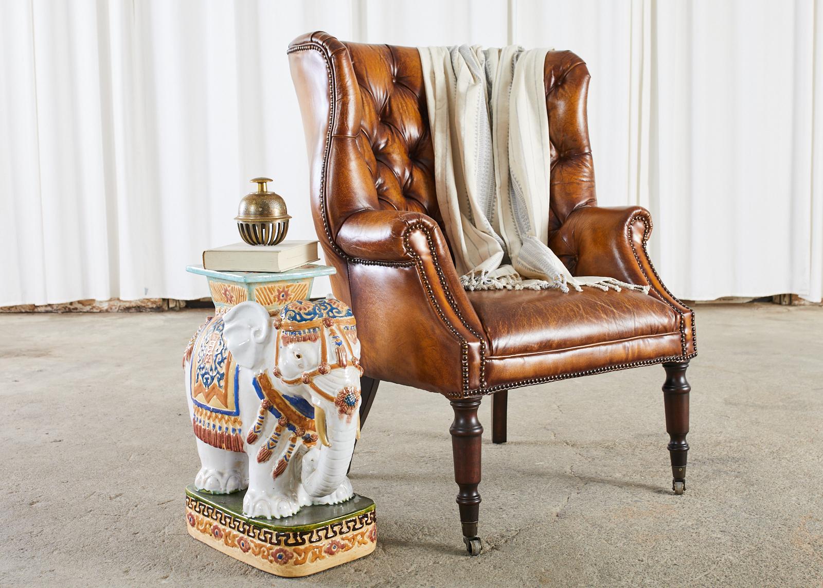 Handsome pair of cigar leather wing chairs or wingback chairs made in the grand English Georgian taste. The chairs feature a large hardwood frame with rolled arms and fully developed wings in a 