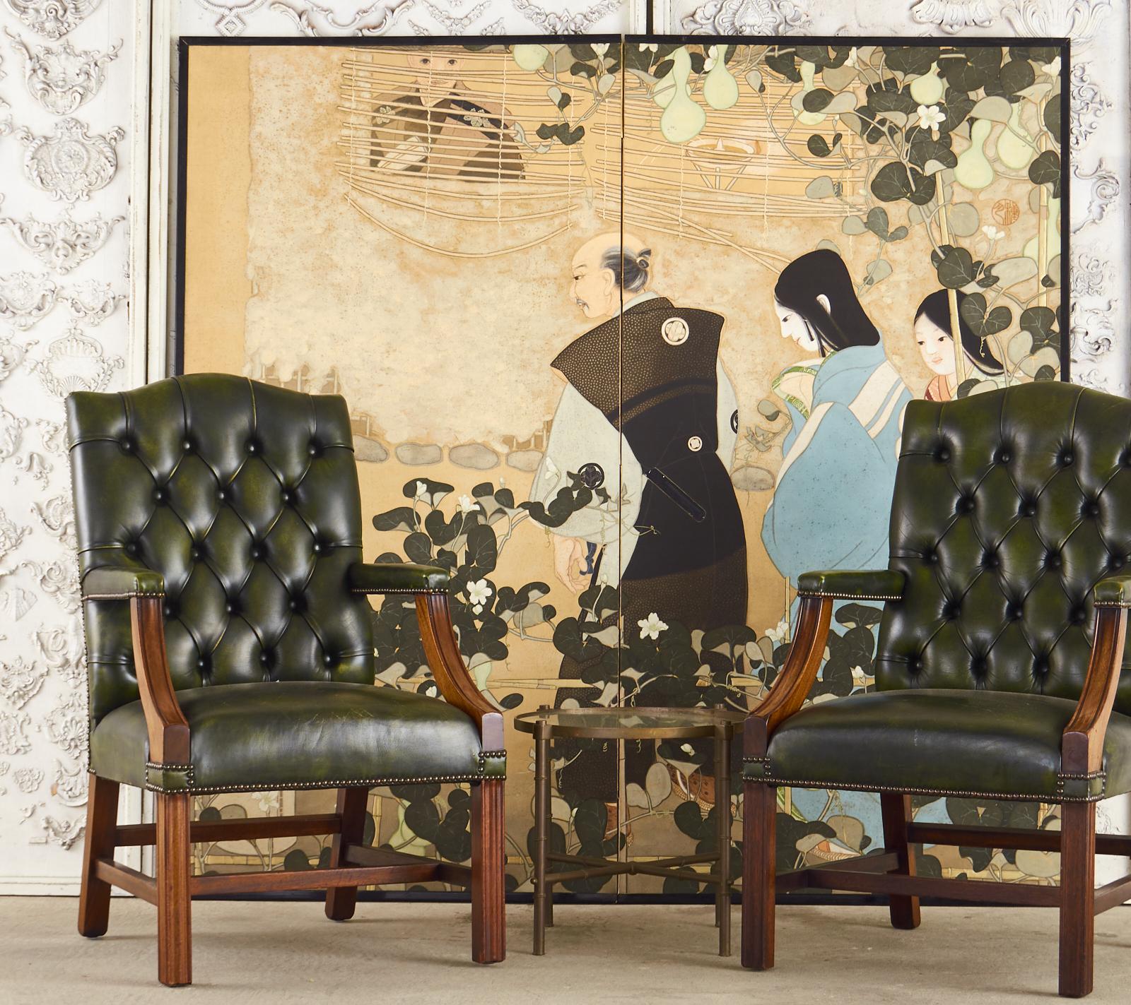 Regal pair of English Gainsborough library armchairs made in the Georgian taste. The chairs feature a hardwood mahogany frame covered with a rich, dark green leather having a tufted chesterfield style back rest. Classic Gainsborough design with a