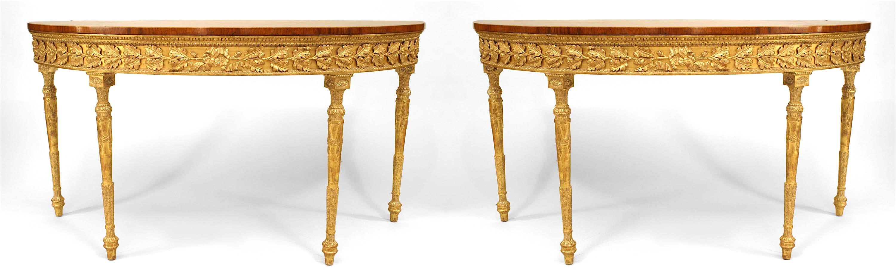 Pair of English Georgian-style (19th Century) satinwood demilune shaped console tables with mahogany banding inlaid with scrolling design over a gilt & applied floral carved apron & legs. (PRICED AS Pair)
