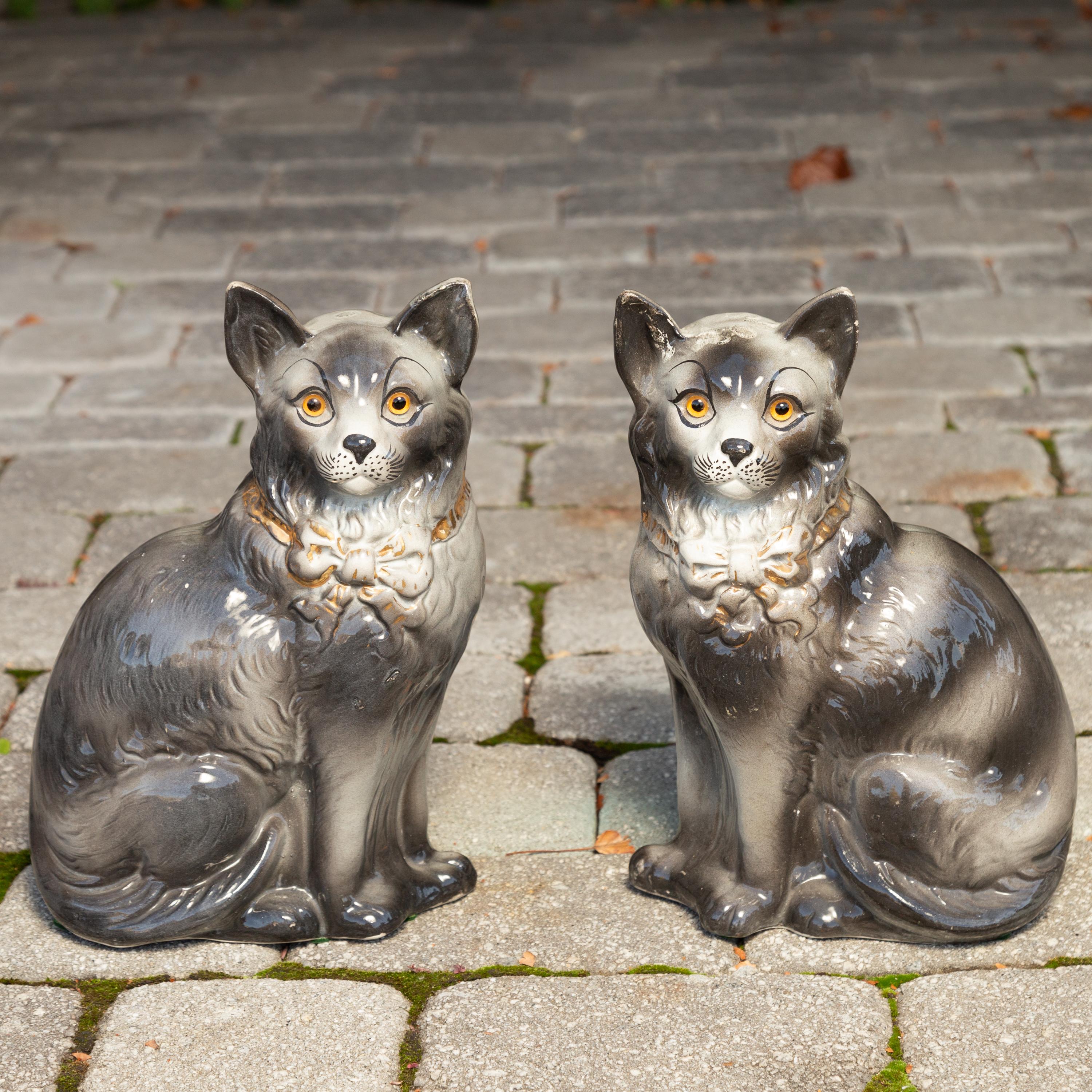 A pair of English Staffordshire cats from the late 19th century with grey coats and ribbons. Born in England during the laters years of Queen Victoria's long reign, this pair of Staffordshire sculptures features two grey-coated cats wearing delicate