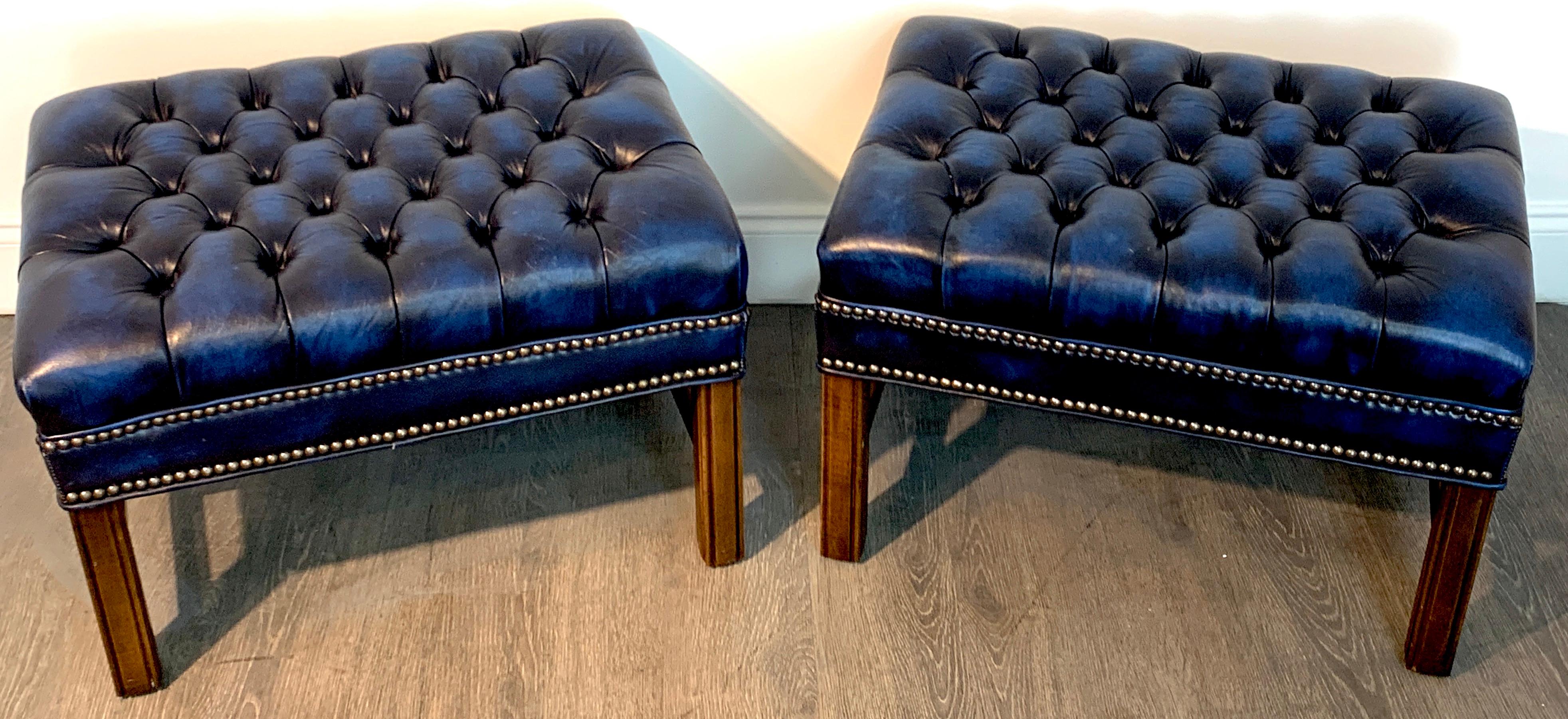 Pair of English Hollywood Regency blue leather chesterfield benches/ottomans, each one with tufted and nailhead detail, custom hand dyed shaded blue leather upholstery raised on four mahogany Marlborough legs, with 'H' stretcher. Clean and simple