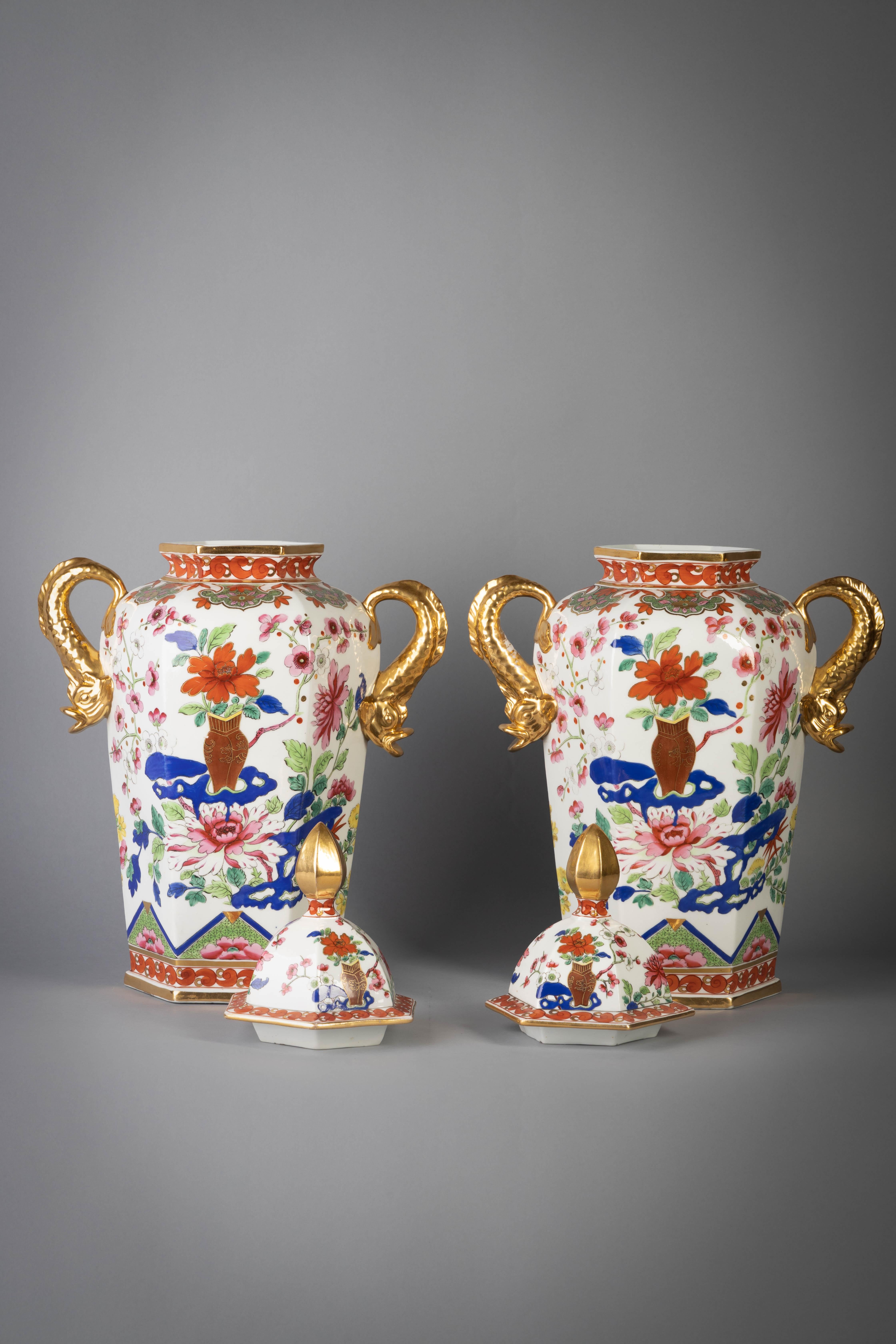 Each of hexagonal form with gilt dolphin handles, painted in the famille rose palette and enriched with blue, the front and back with chrysanthemum issuing from a brown vase and flowering peony and flowering branches, the covers similar decorated