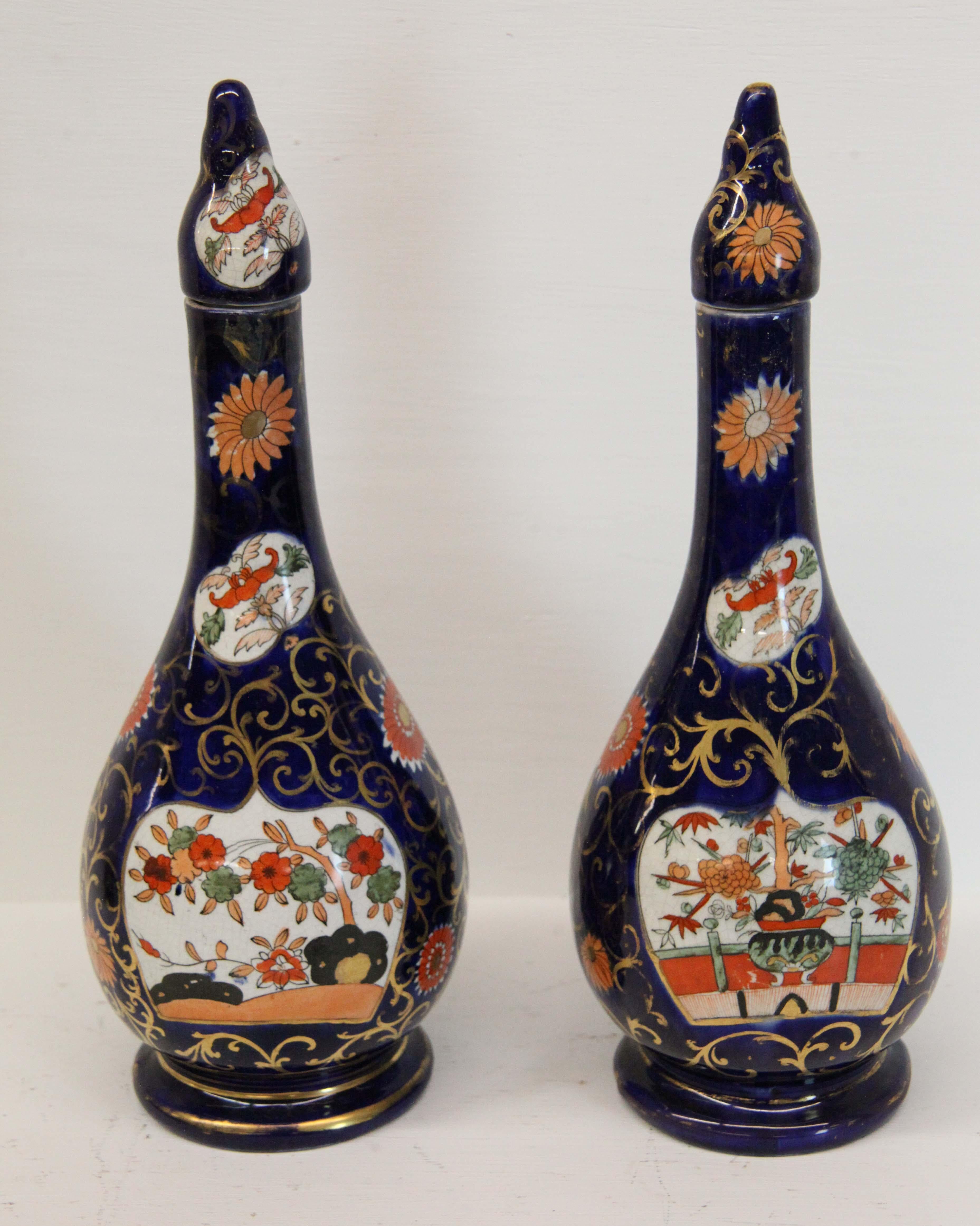 Pair of English ironstone vases with lids, unusual long neck form, the lower portion with floral and foliate filled panels, the cobalt background accented with gilt arabesques.
