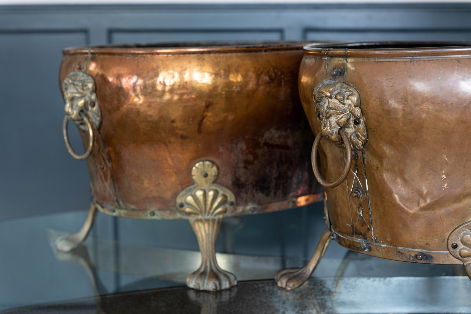 Pair of English late 19th century copper and brass lion paw coal buckets/planters
Riveted copper and brass detailing with matching lion head rings and lion paw feet.
A few dents with areas of verdigris and rustic patina.
One has perforated holes