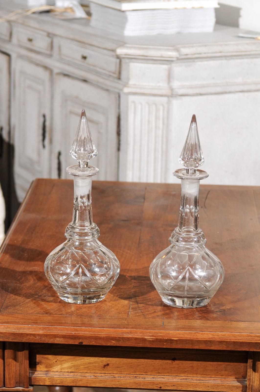 A pair of English late Victorian cut crystal decanters from the mid-19th century with their stoppers. Born in England during the second half of the 19th century, each of this pair of decanters features a round belly, adorned with delicately cut