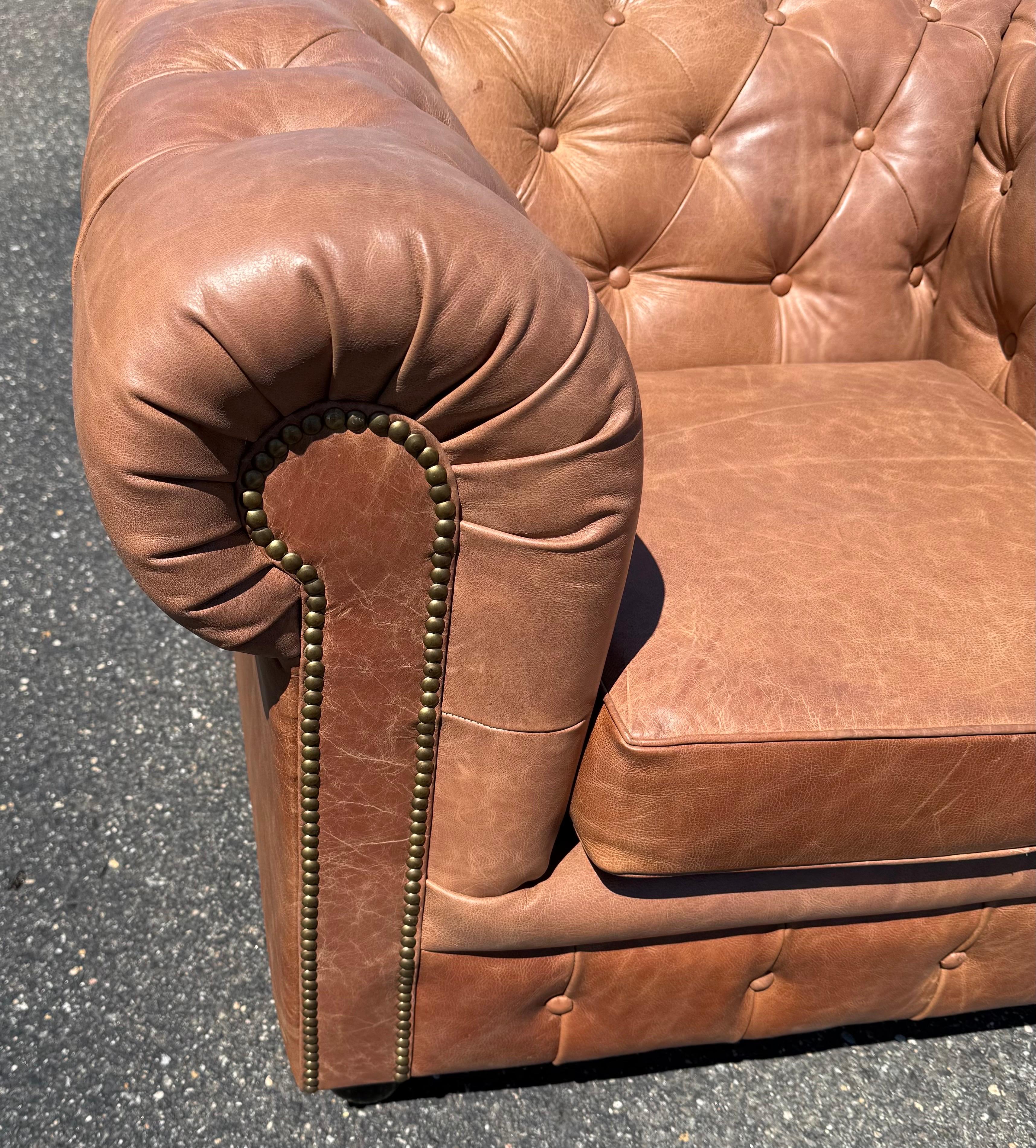 This exceptional pair of English-made leather club chairs showcases traditional craftsmanship with a bold, masculine presence. Upholstered in heavily distressed natural leather in a rich gingerbread cinnamon hue, these chairs radiate warmth and