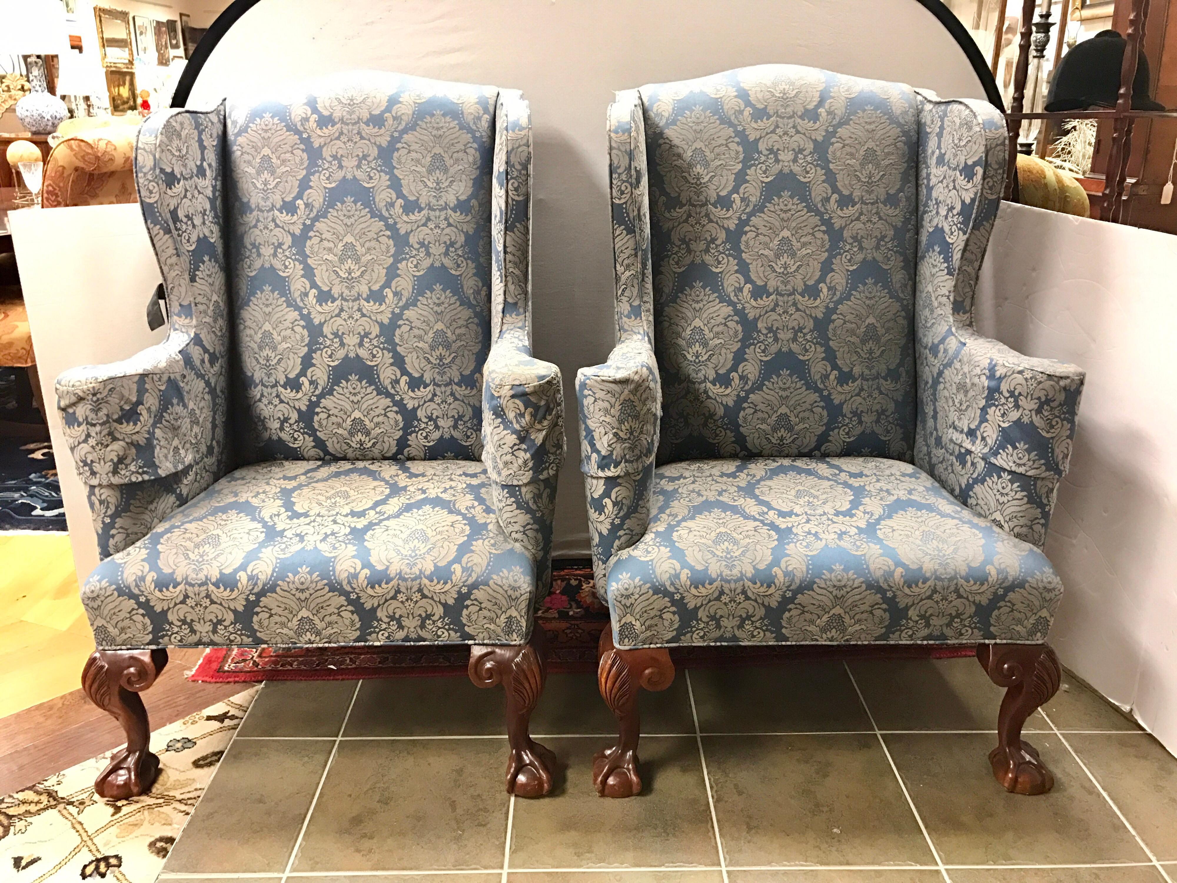 Magnificent pair of English mahogany wingbacks feature ball and claw feet in the front and back. They are upholstered in a luxurious blue damask fabric.  Would look great as fireplace chairs or as end chairs for a dining room table.
They are to die