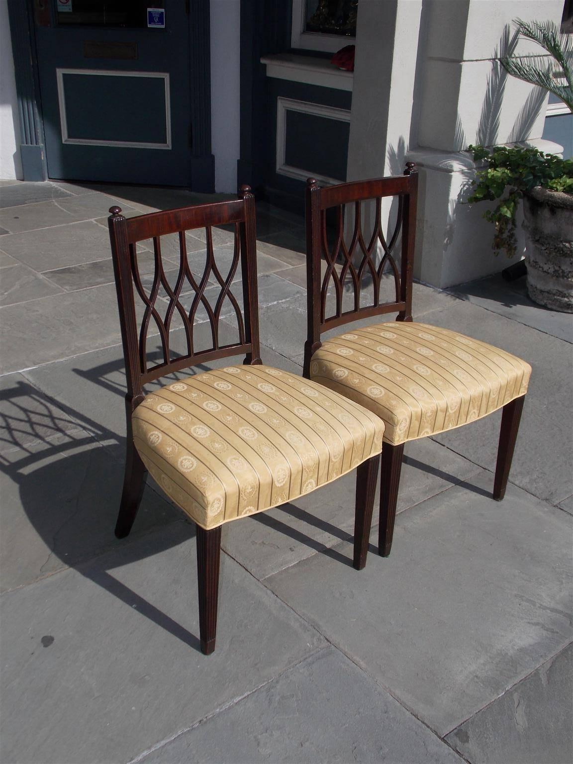Pair of English mahogany Sheraton side chairs with flanking ball finials, reeded side rails, crosshatching splat backs, upholstered silk striped seats and terminating on the original tapered reeded legs, Early 19th century.