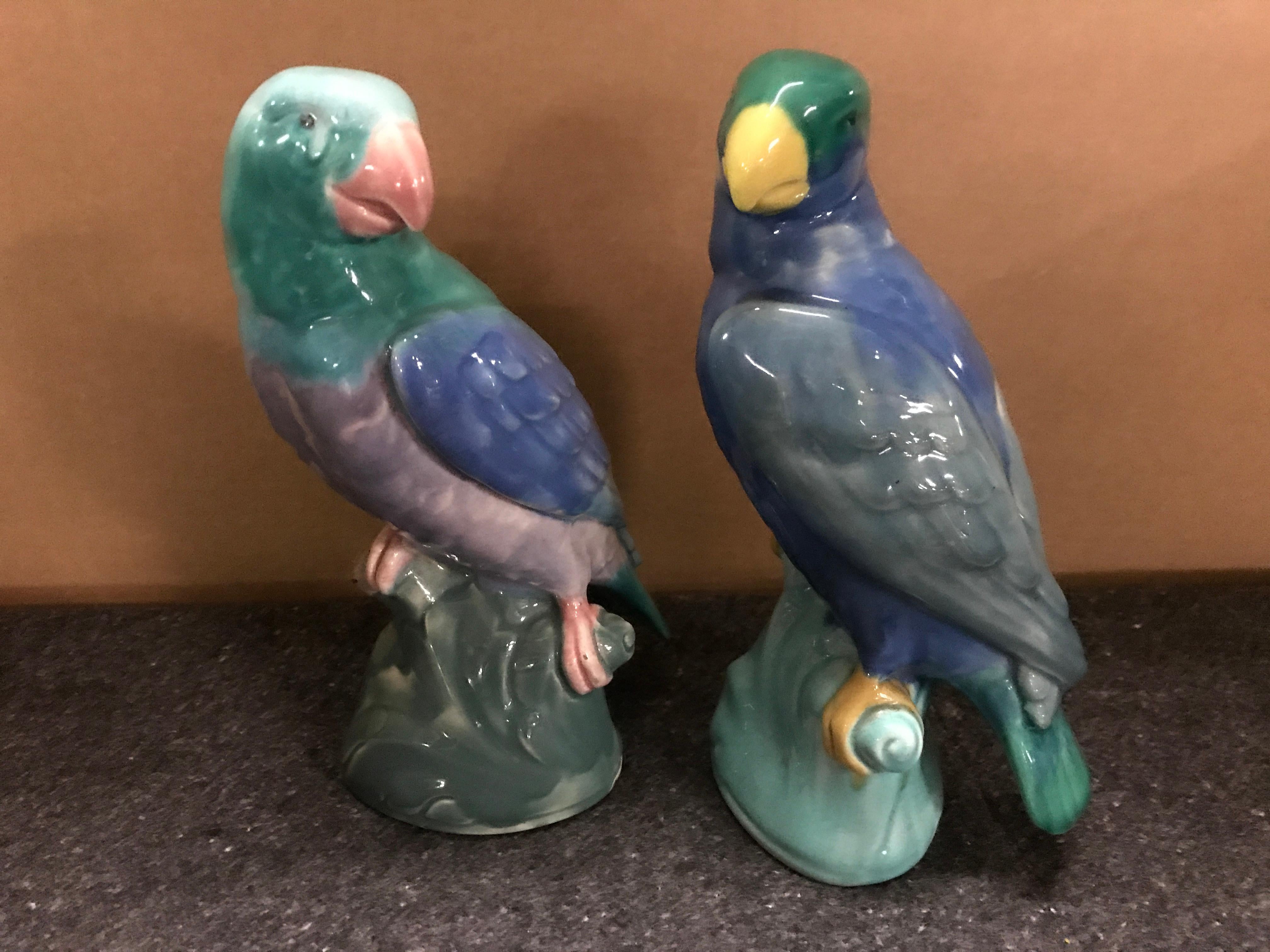 Pair of English Majolica parrot figures by Mintons, each one with colorful feathers, resting on a perch.
  
