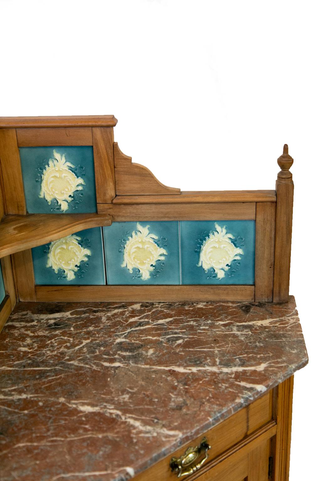 Pair of English marble-top corner cabinets, each retaining the original majolica tiles in the backs, marble, and hardware. The drawers have raised panels and the top sections have turned finials and shallow corner shelves.
 