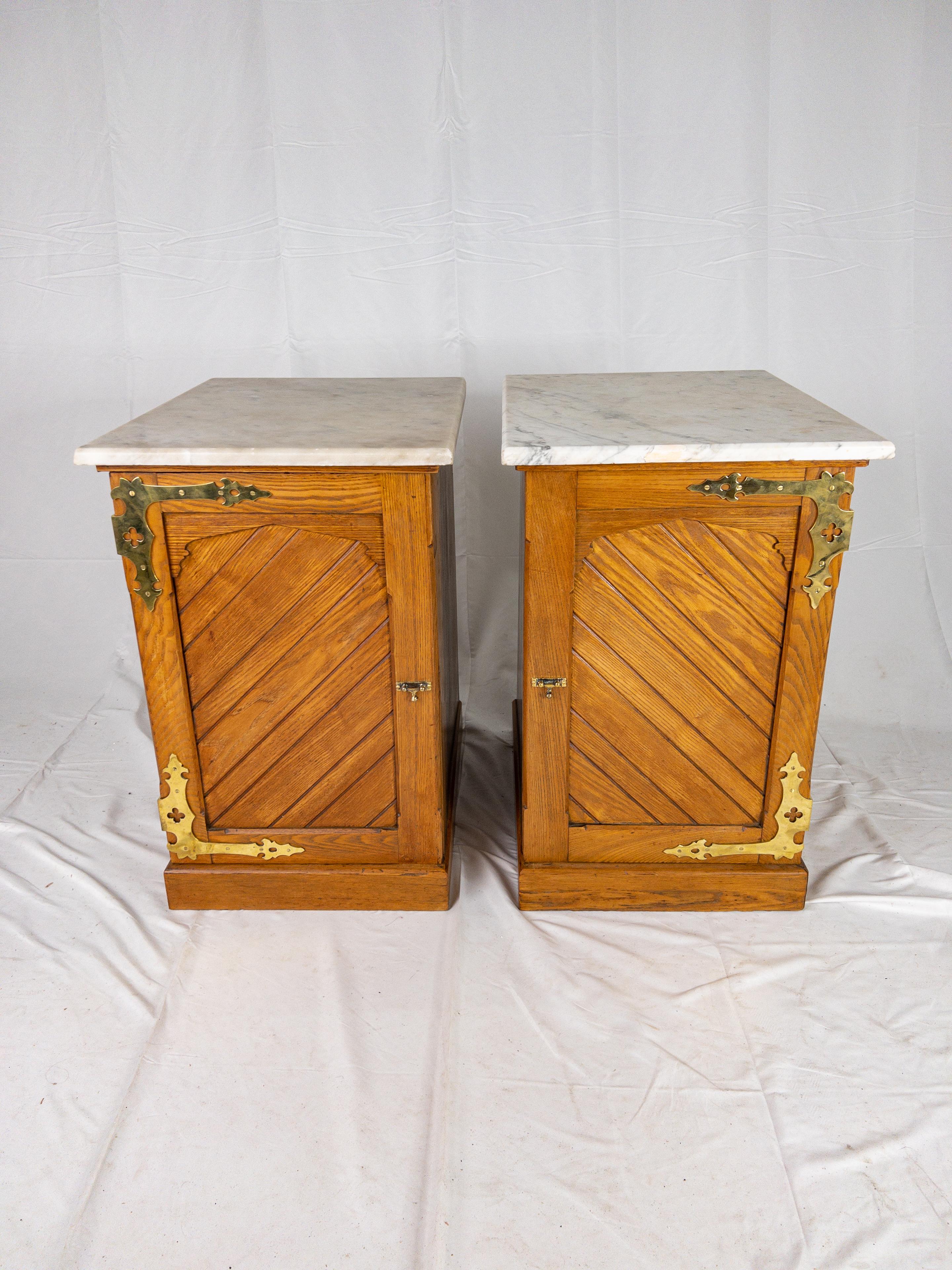 Pair of English Marble Top Side Cabinets having beveled marble tops and a plinth base. The cabinets have doors with a diagonal wood pattern and prominent brass hardware.

Please review all images as they are considered part of the item description.
