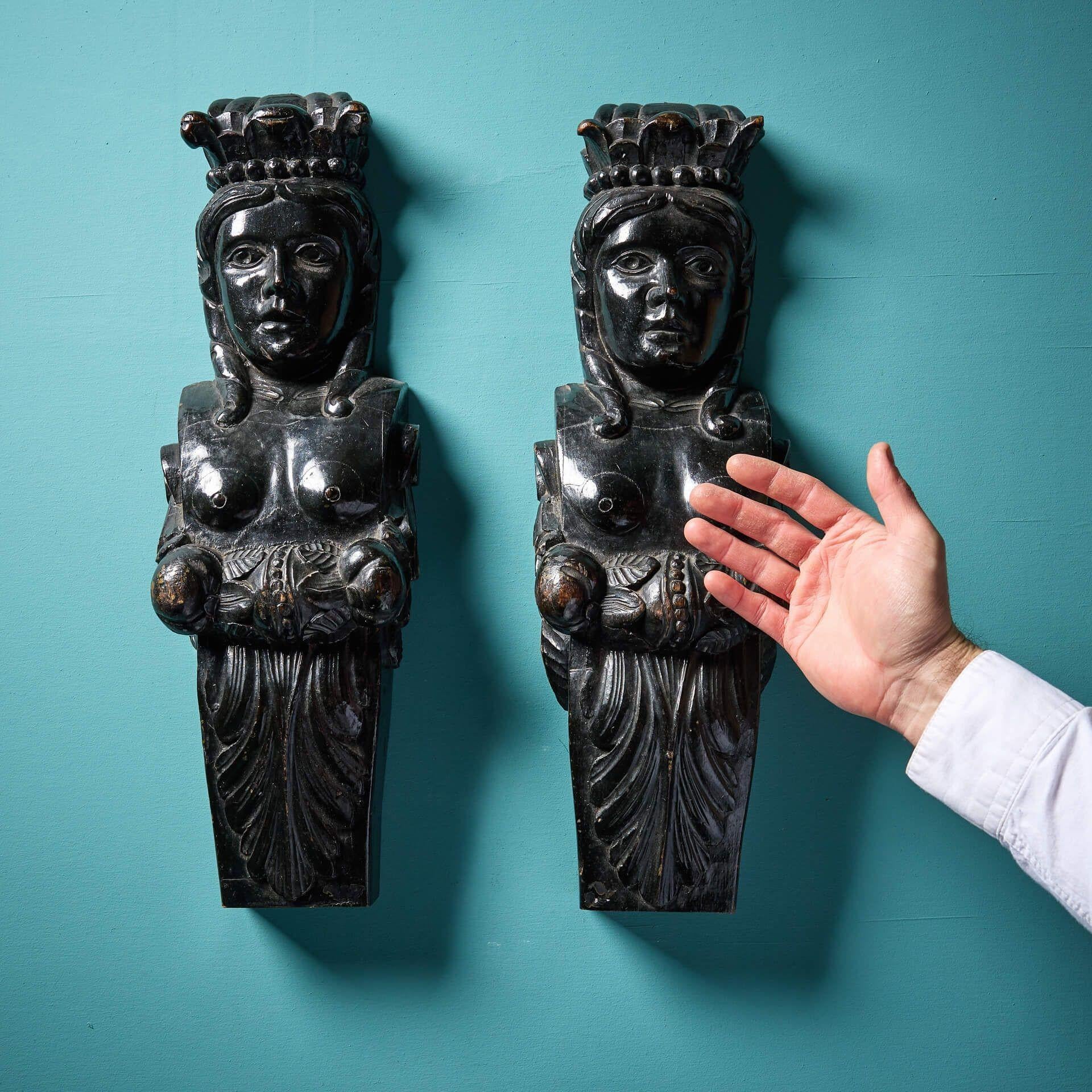 Coppia di cariatidi femminili in stile medievale inglese del XIX secolo, scolpite come regine o valchirie. Queste sculture hanno un design coordinato e raffigurano ciascuna una maschera femminile con corona sopra una staffa a scorrimento in una