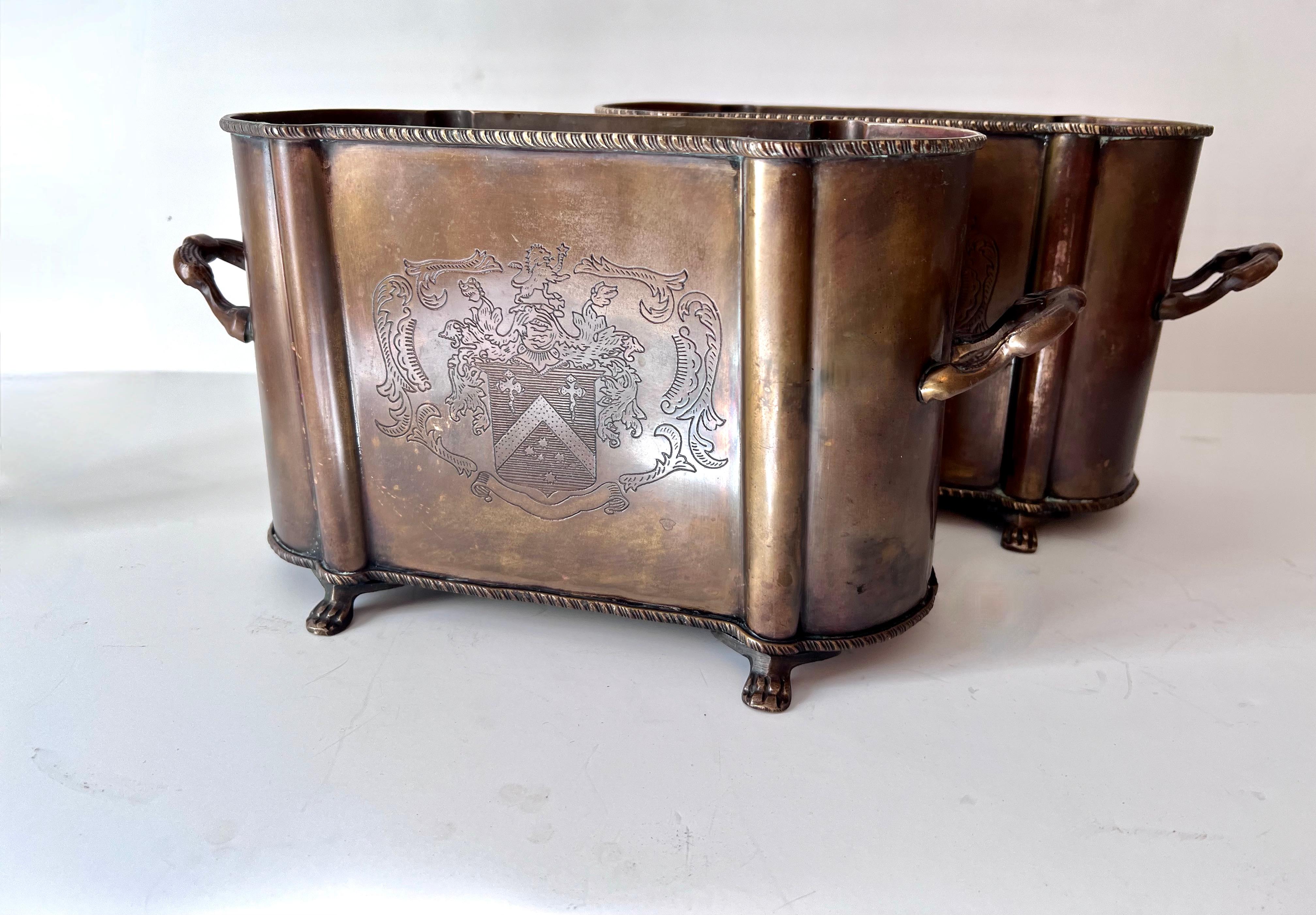 Pair of cachepots or jardinieres of metal with handles and claw feet. The pair are well patinated and would work well flanking a door way or fireplace mantle... could be used as planters, or for kindling - or purely decorative. 

They have a crest