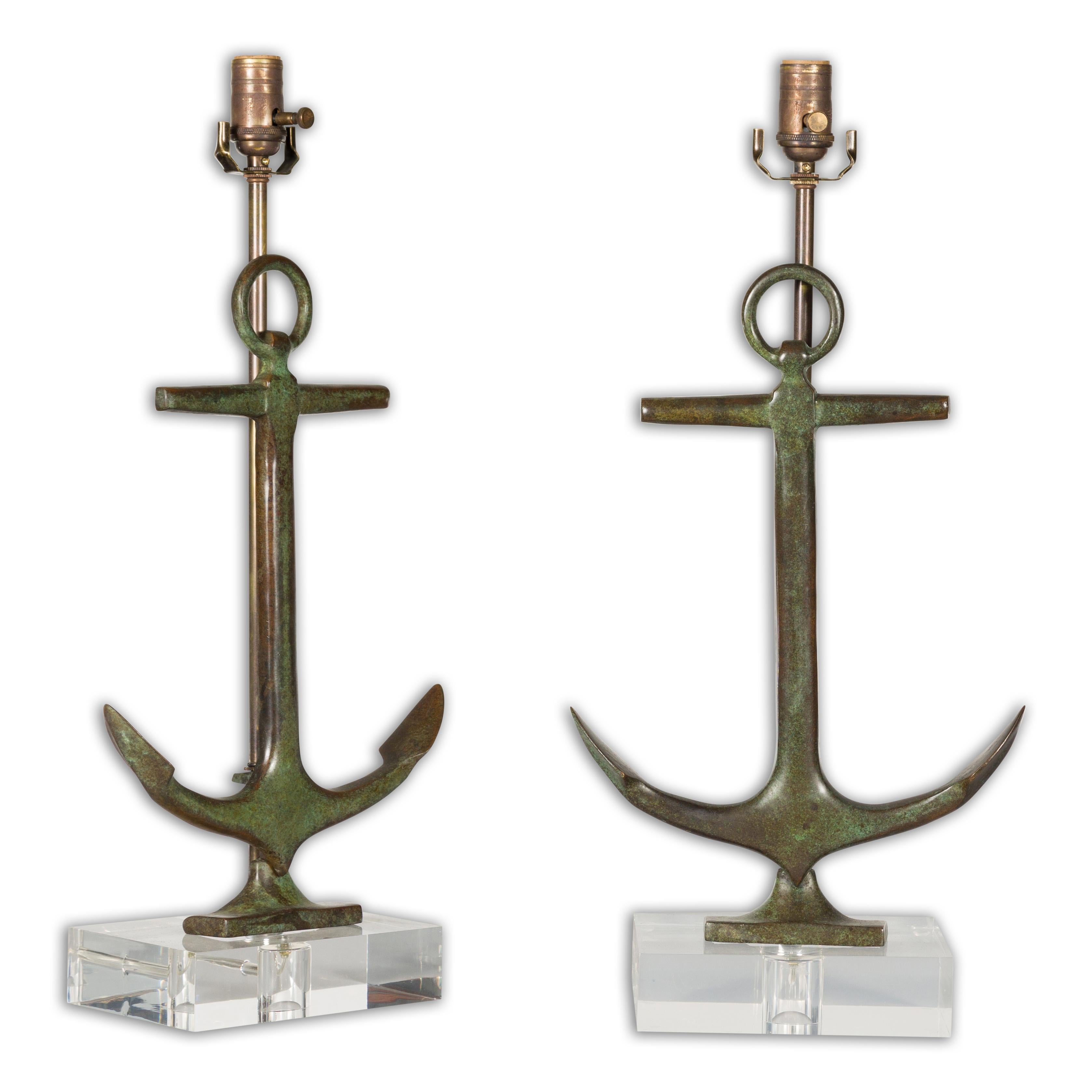 A pair of English Midcentury bronze table lamps depicting anchors mounted on custom made rectangular shaped lucite bases. Add a nautical touch to your decor with this pair of English Midcentury bronze table lamps, artfully cast into the form of