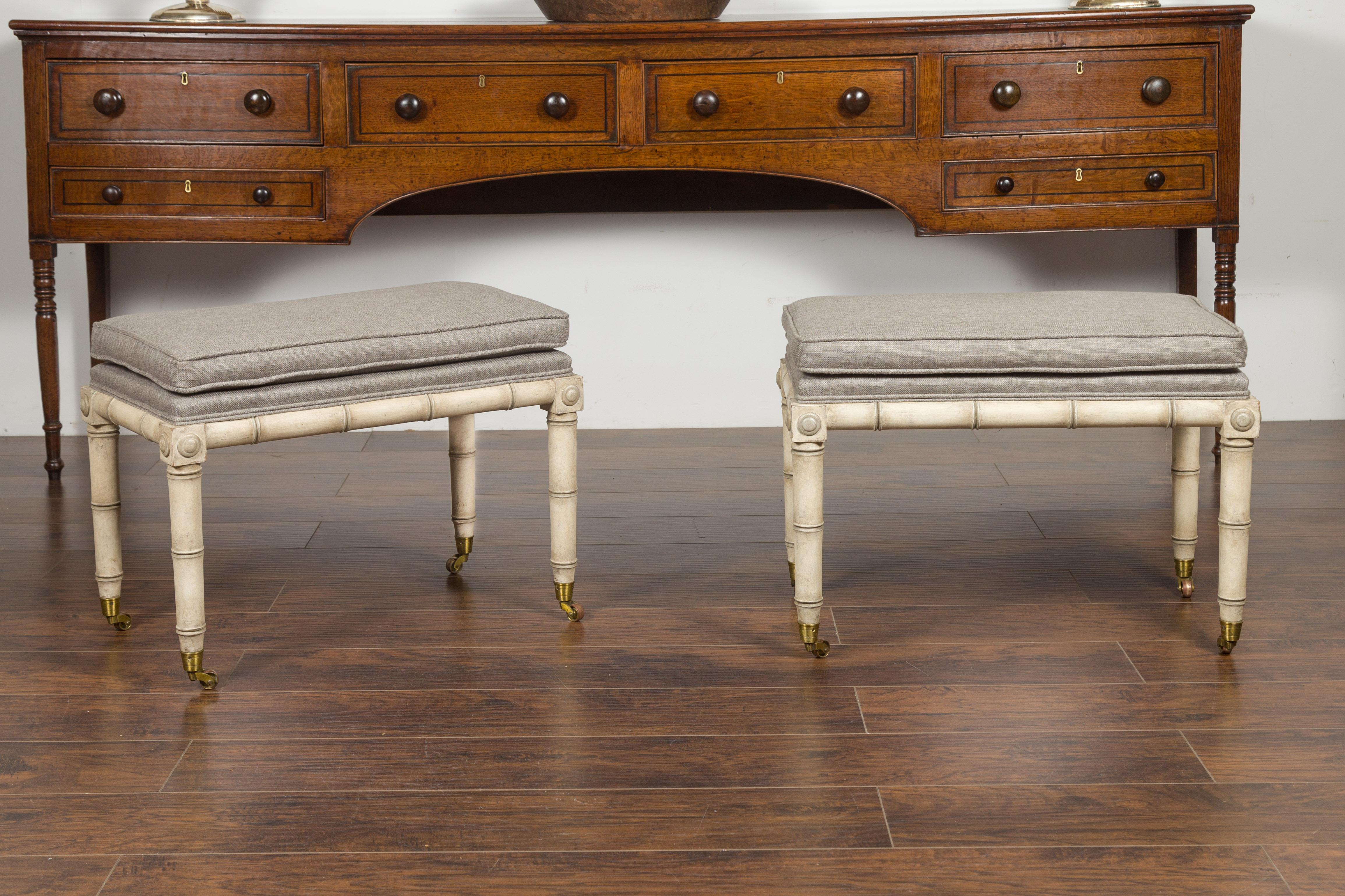 A pair of English vintage painted faux-bamboo benches from the mid-20th century, with carved medallions, casters and new upholstery. Created in England during the midcentury period, each of this pair of freshly painted benches features a rectangular