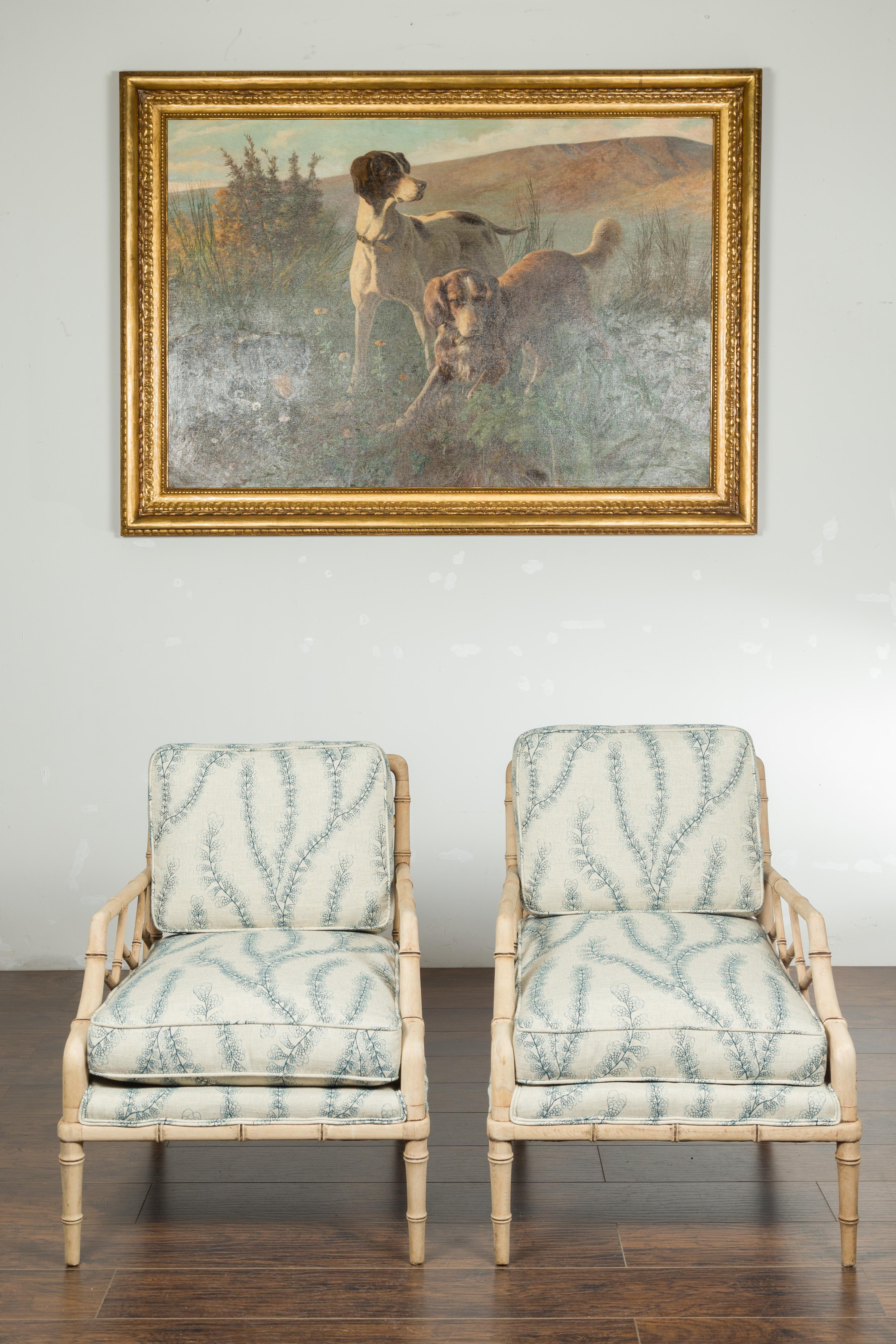 A pair of English walnut lounge chairs from the mid 20th century, with faux bamboo structure and foliage-themed upholstery. Created in England during the midcentury period, each of this pair of armchairs features bleached walnut faux bamboo arms,
