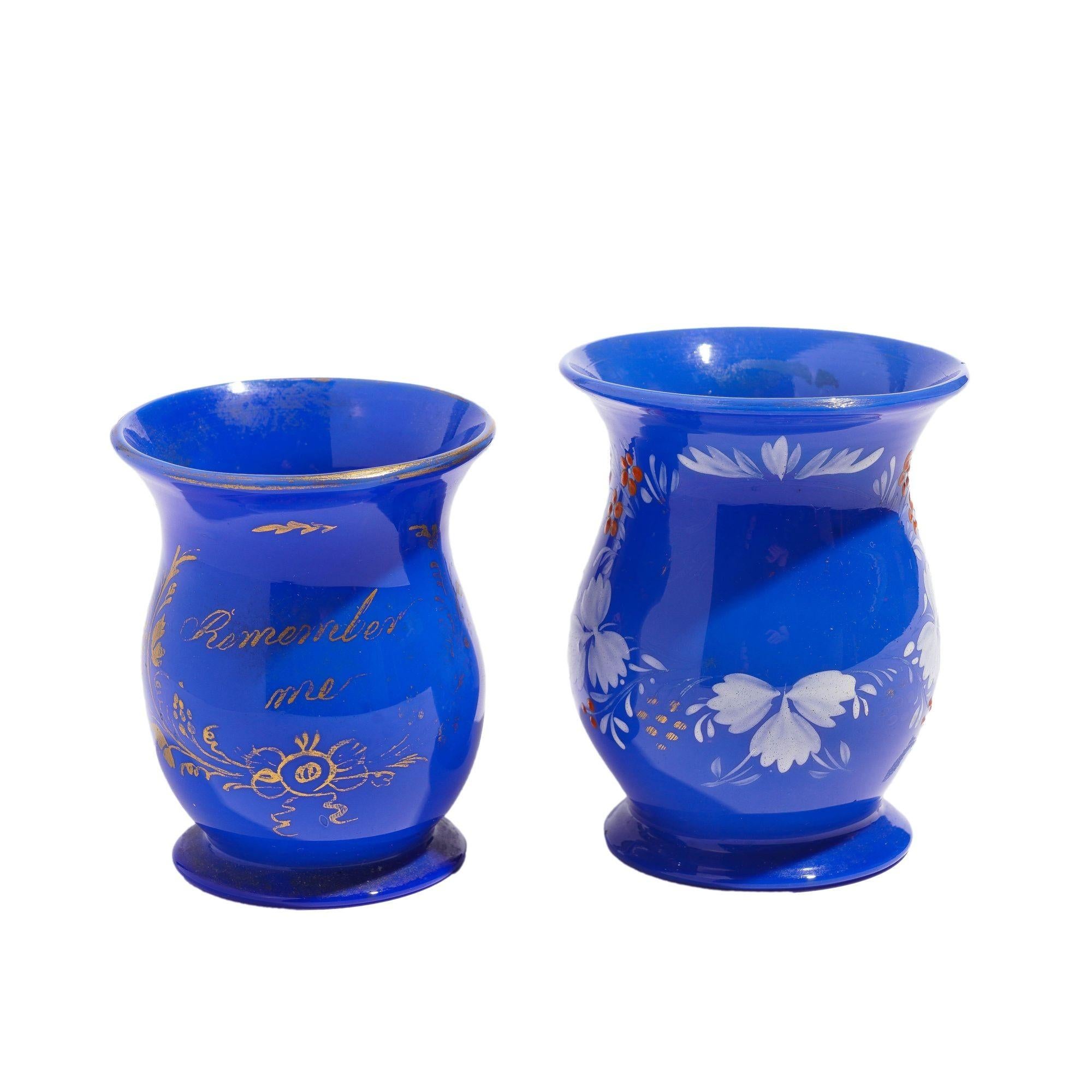 Pair of miniature blue opaline blown glass mugs with applied handle and gilt & enamel decoration.
Bristol, England, circa 1830.

Dimensions: 3-1/2” L x 2-3/4” W x 3-1/2” H
3-1/4” L x 2-1/2” W x 3” H