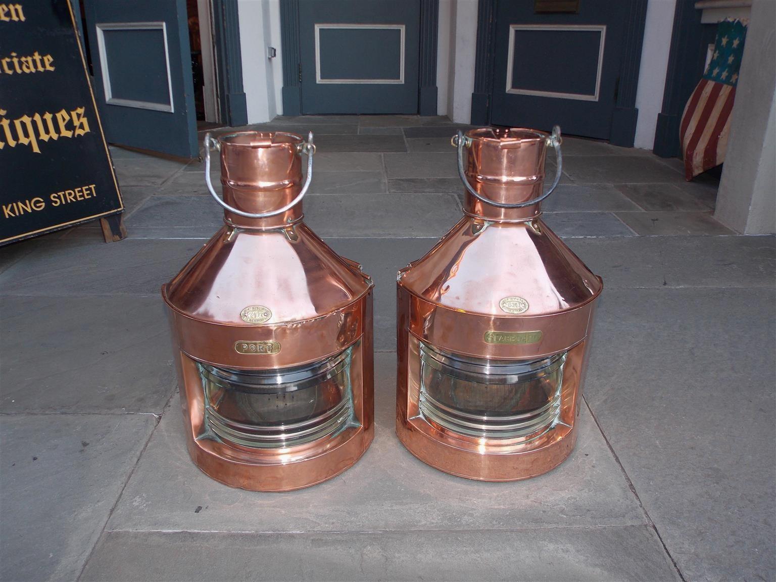 Pair of English nautical copper and brass port and starboard ship lanterns with polished steel carrying handles, vented tops, original Fresnel lenses, brass stamped badges, rear handles with sliding doors, and original mounting brackets. Stamped
