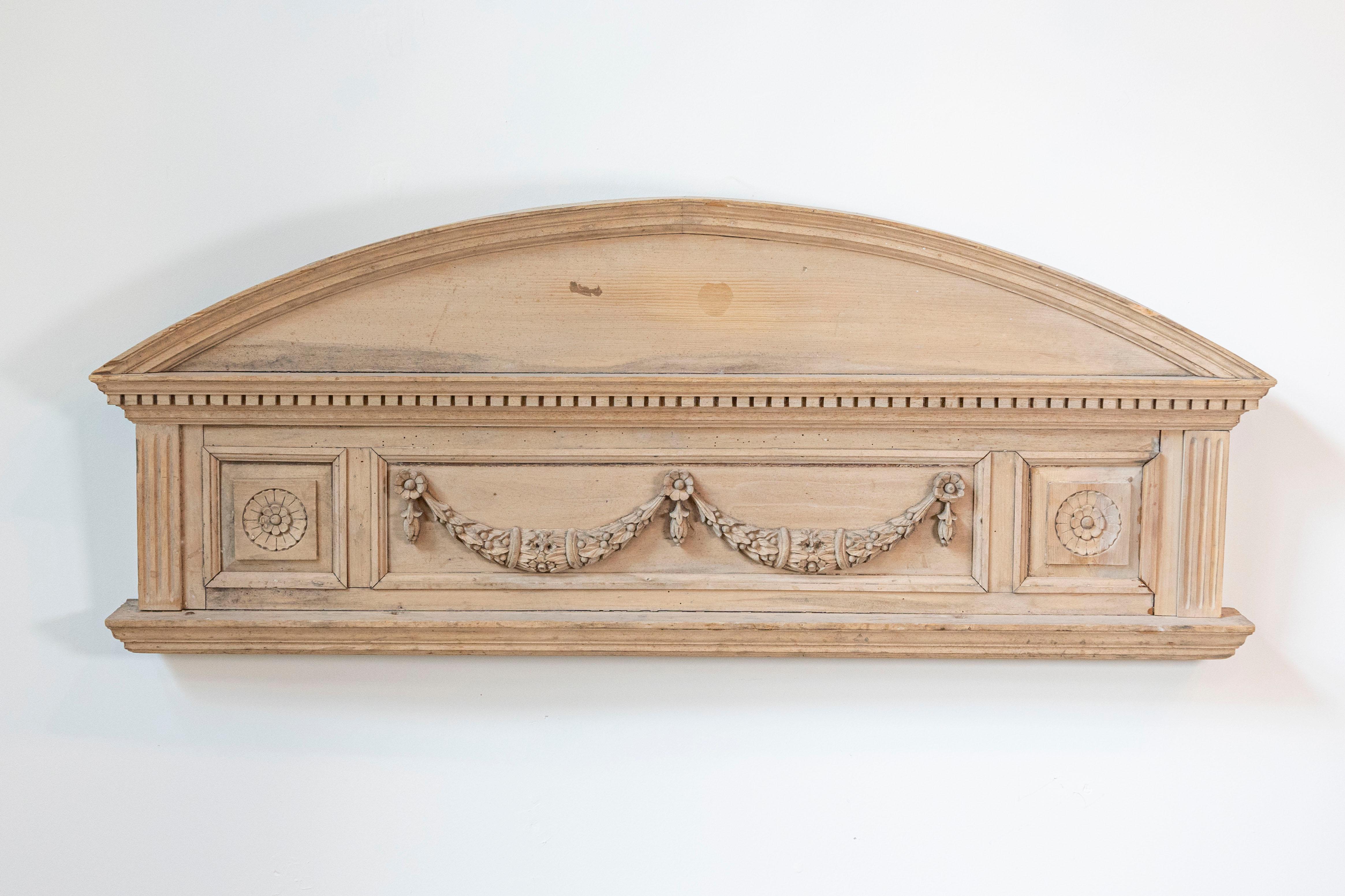 Paire de portes en pin sculpté de style néoclassique anglais, avec des motifs en forme de guirlandes et des moulures en denticules, datant du milieu du 19e siècle. Cette paire d'éléments architecturaux anglais se caractérise par un fronton incurvé,