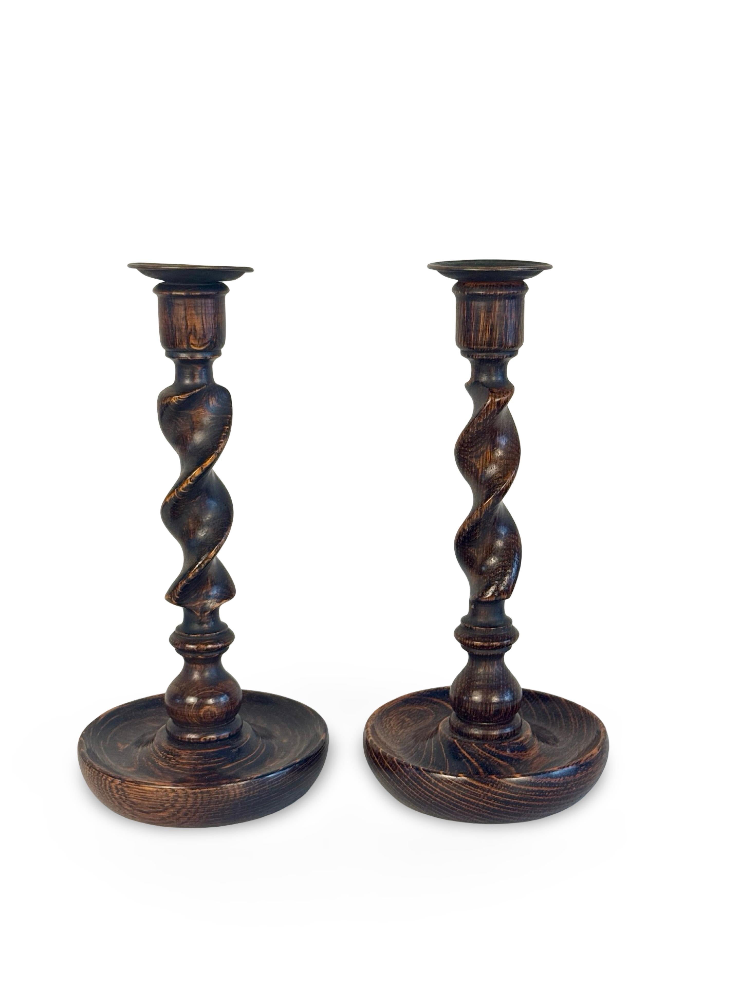 Bellissima coppia di candelieri inglesi in legno di quercia tornito, i cui steli a spirale poggiano su basi a forma di piatto finemente intagliate, sormontate da bobeches in ottone. Fine del XIX o inizio del XX secolo.