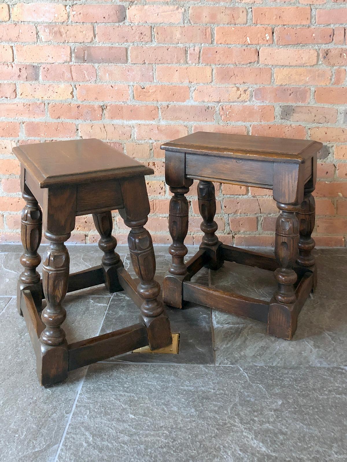 A charming pair of English Oak Elizabethan style stools or small end tables, of solid construction and typical form, the tops with molded edges above a plain frieze, the fluted baluster turned legs joined all around by plain stretchers.
  