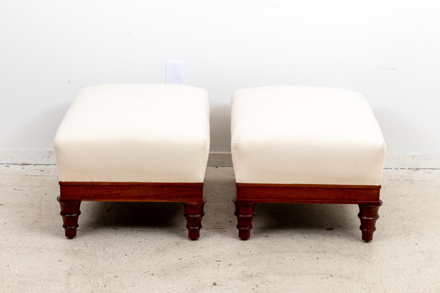Pair of newly upholstered English style ottomans with tapered, ring turned legs. Please note of wear consistent with age including minor finish loss to the wood.