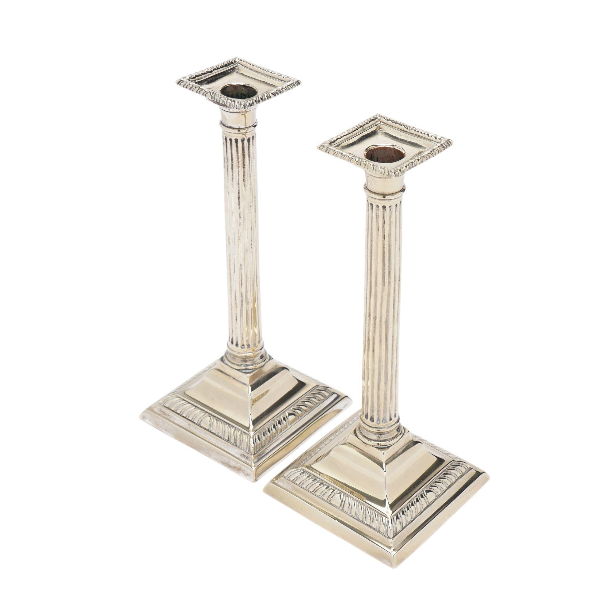 Pair of English cast Paktong columnar candlesticks with a gadroon edged square bobesh. The fluted columnar shaft rests on a plinth which is mounted above a sloped base, edged with a gadrooning. Cast in two parts, the base peened to the shaft, and