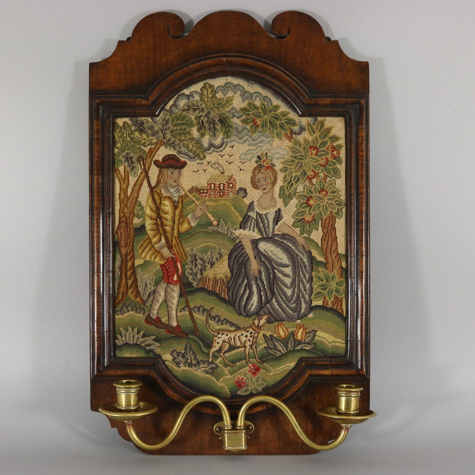 Una coppia di pannelli agugliati a piccolo punto, incorniciati in cornici di noce, con bracci a candela e applique montate sul fondo. Nello stile degli originali dell'inizio del XVIII secolo, ma lavorati nel 1900 circa. Una con una coppia sotto gli