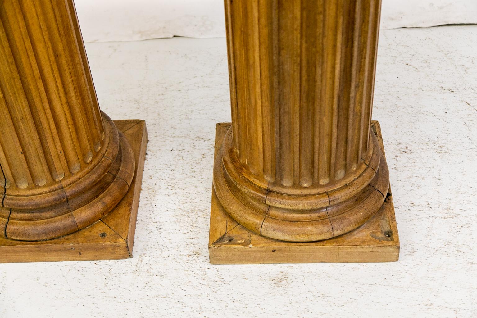 Pair of English pine fluted columns, with capitals that are elaborately carved in a modified Corinthian style. The columns are fluted from top to bottom and terminate in turned bases resting on square plinths. The diameter is 11”, they are 15.5”