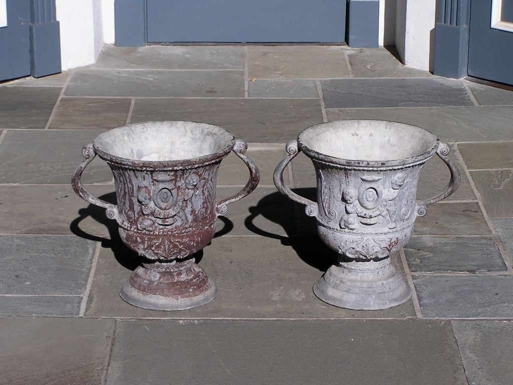 Paire d'urnes de jardin anglaises en plomb polychromé, chacune avec des poignées à volutes, des chérubins et des feuilles d'acanthe, et se terminant sur des plinthes circulaires en forme de dôme, début du XIXe siècle. 
Les urnes mesurent 17,5