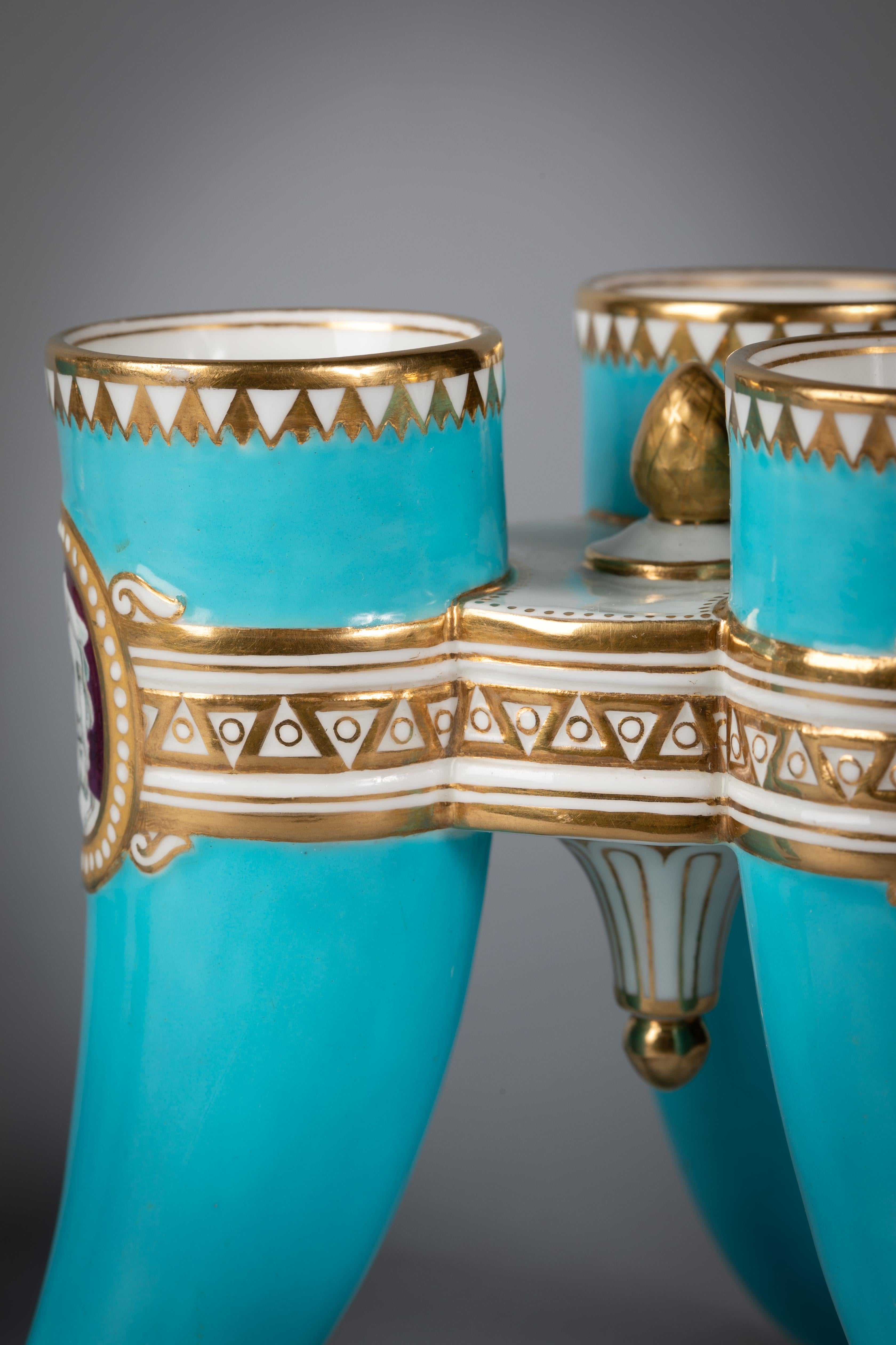 Pair of English porcelain turquoise ground three-footed vases, Minton, Dated 1865.

Each Horn-shaped leg with a different cameo bust. Impressed Minton.