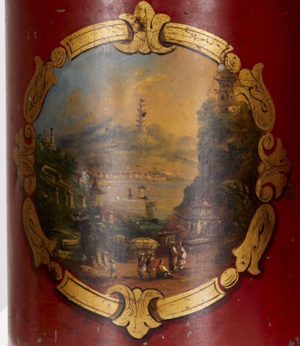 Fine del XIX secolo, Inghilterra, coppia di lampade da tavolo a tole in lamiera smaltata rossa, dipinte con paesaggi orientalisti. I paesaggi sono circondati da un bordo dipinto in oro. Ognuno dei due paesaggi mostra una scena diversa. Una mostra
