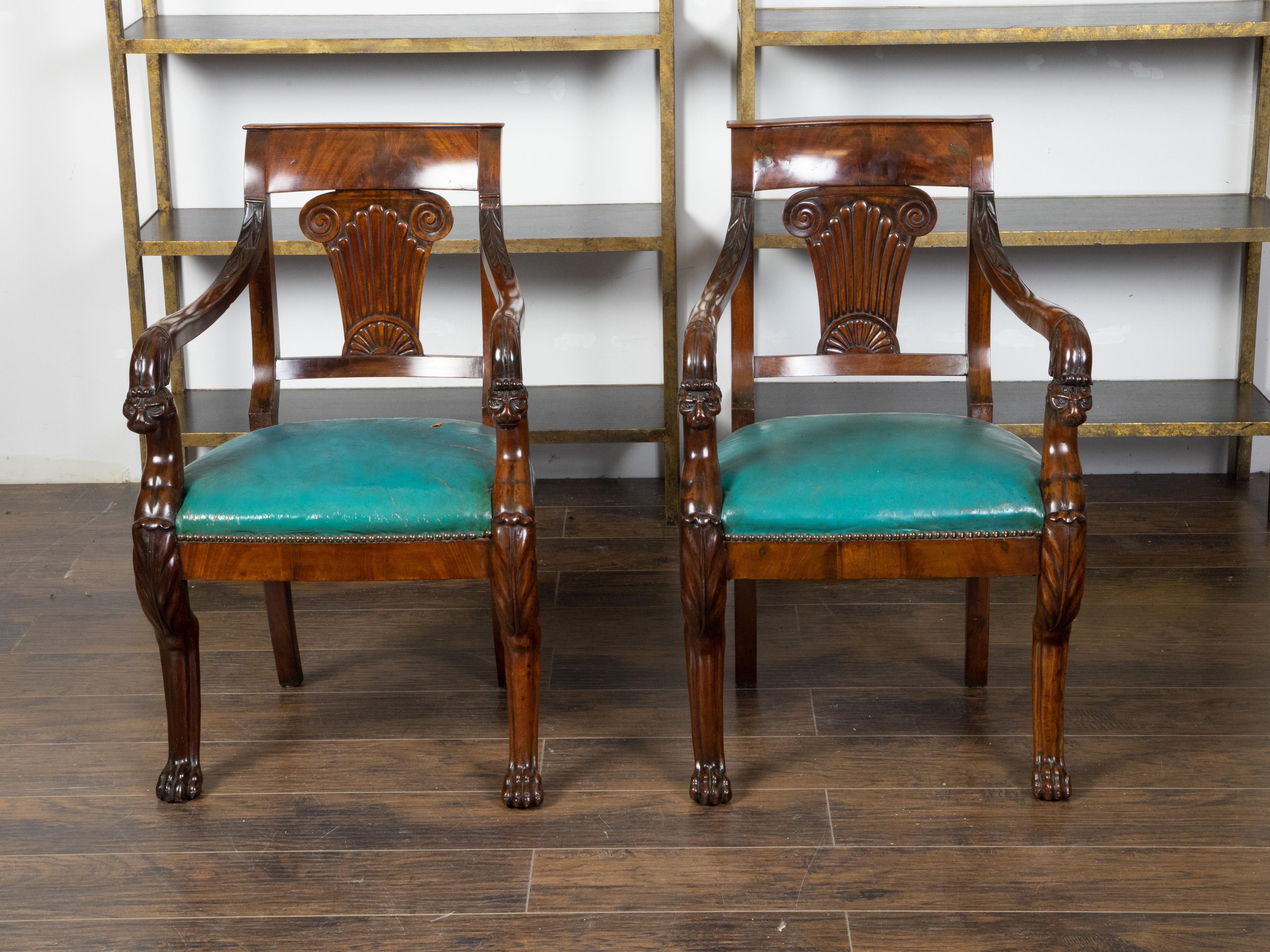 A pair of English Regency period mahogany armchairs from the mid 19th century, with ionic capitals, griffon arms and paw feet. Created in England during the second quarter of the 19th century, each of this pair of armchairs attracts our attention