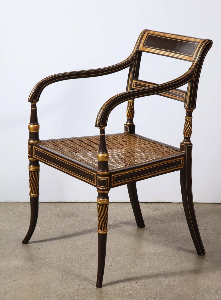 Pair of English Regency Coromandel lacquered and gilt arm chairs with a splat crest and back, sweeping fluted arms, cane hole seats, and terminating on the turned and splayed legs.