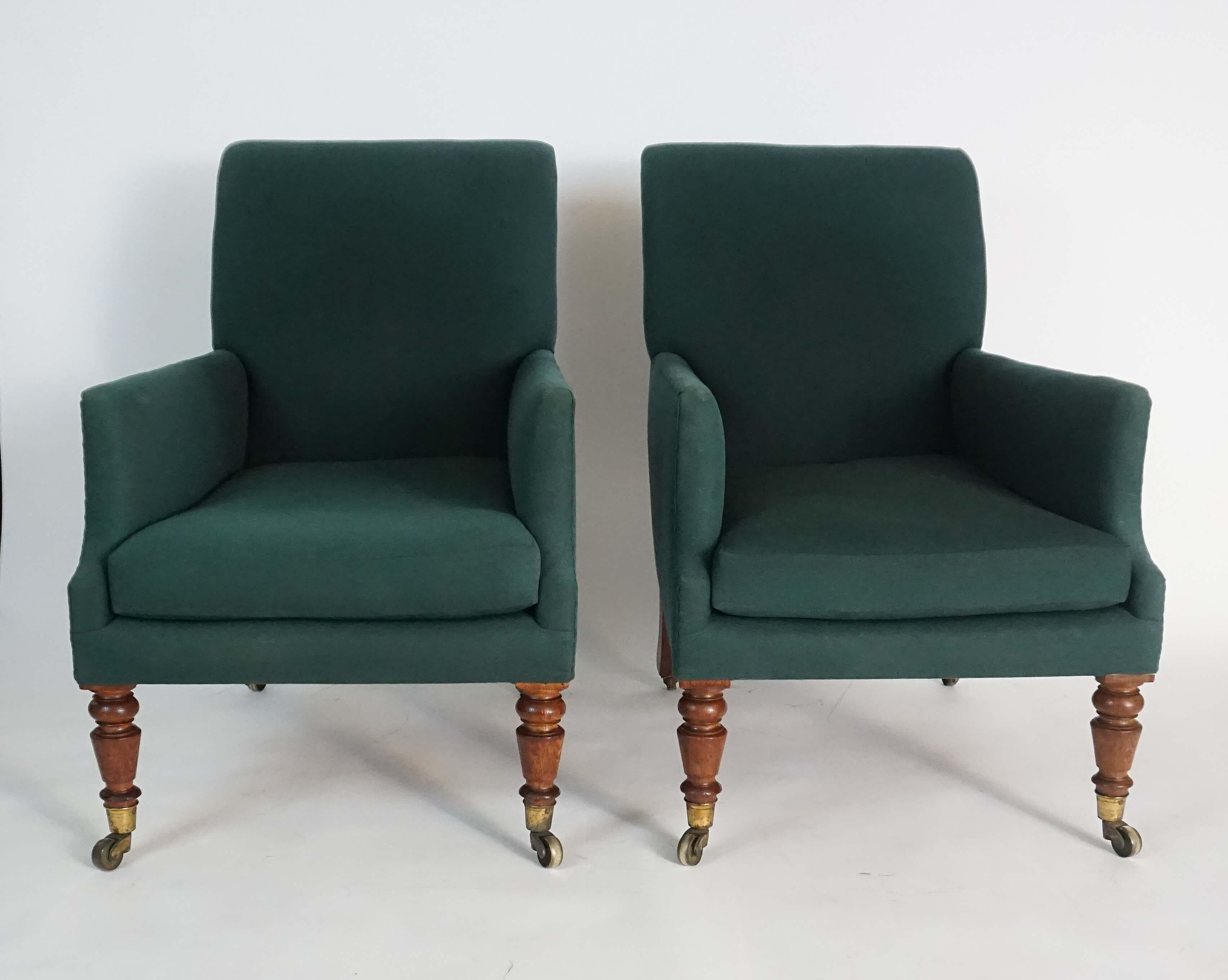 Pair of circa 1830 English Regency bergères of large scale having fully upholstered frames; the curved rectangular backs connecting deep seats with squab cushions and box-form arms on turned oak front legs and splayed rear all on original brass
