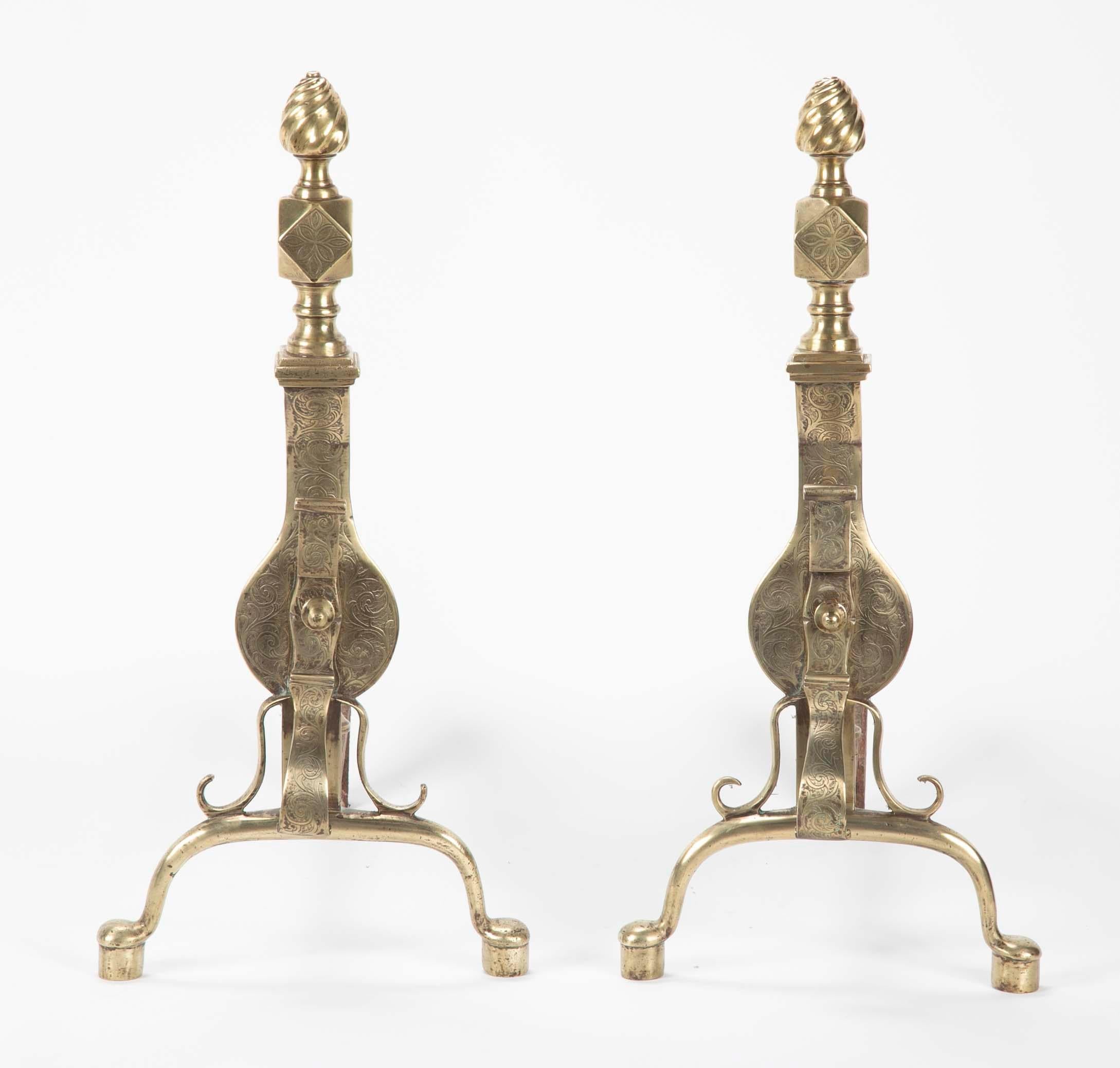 A fine pair of brass andirons with scrolling etched designs. The flame finials over diamond squares above a vase form body held up by cabriole legs. Quite the elegant pair.  
English, early 19th century, Regency period.