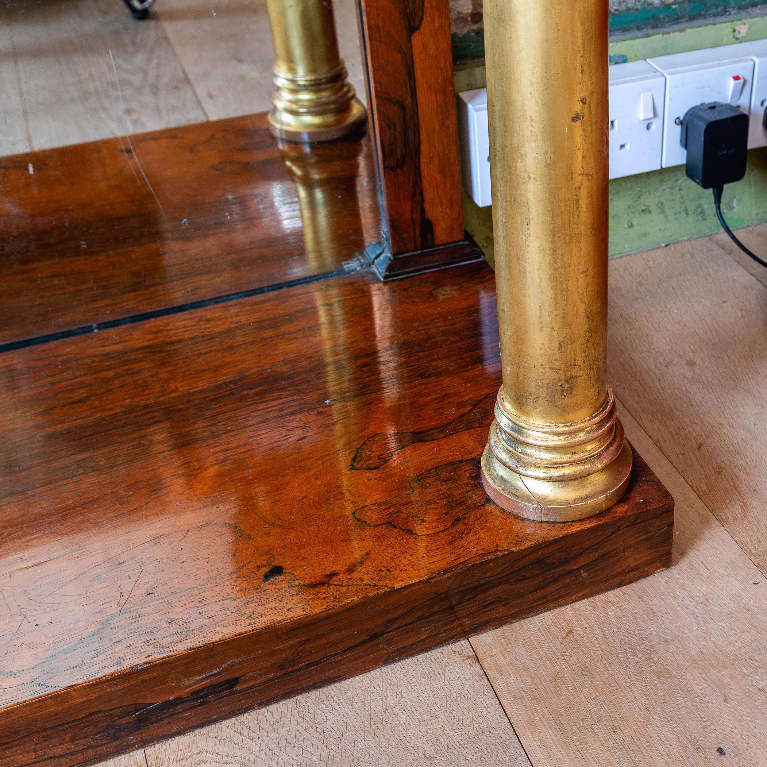 A smart pair of Regency rosewood pier tables, with Statuary marble tops supported on gilded Tuscan columns, with pilasters to the rear flanking mirrored backs, on plinth bases.