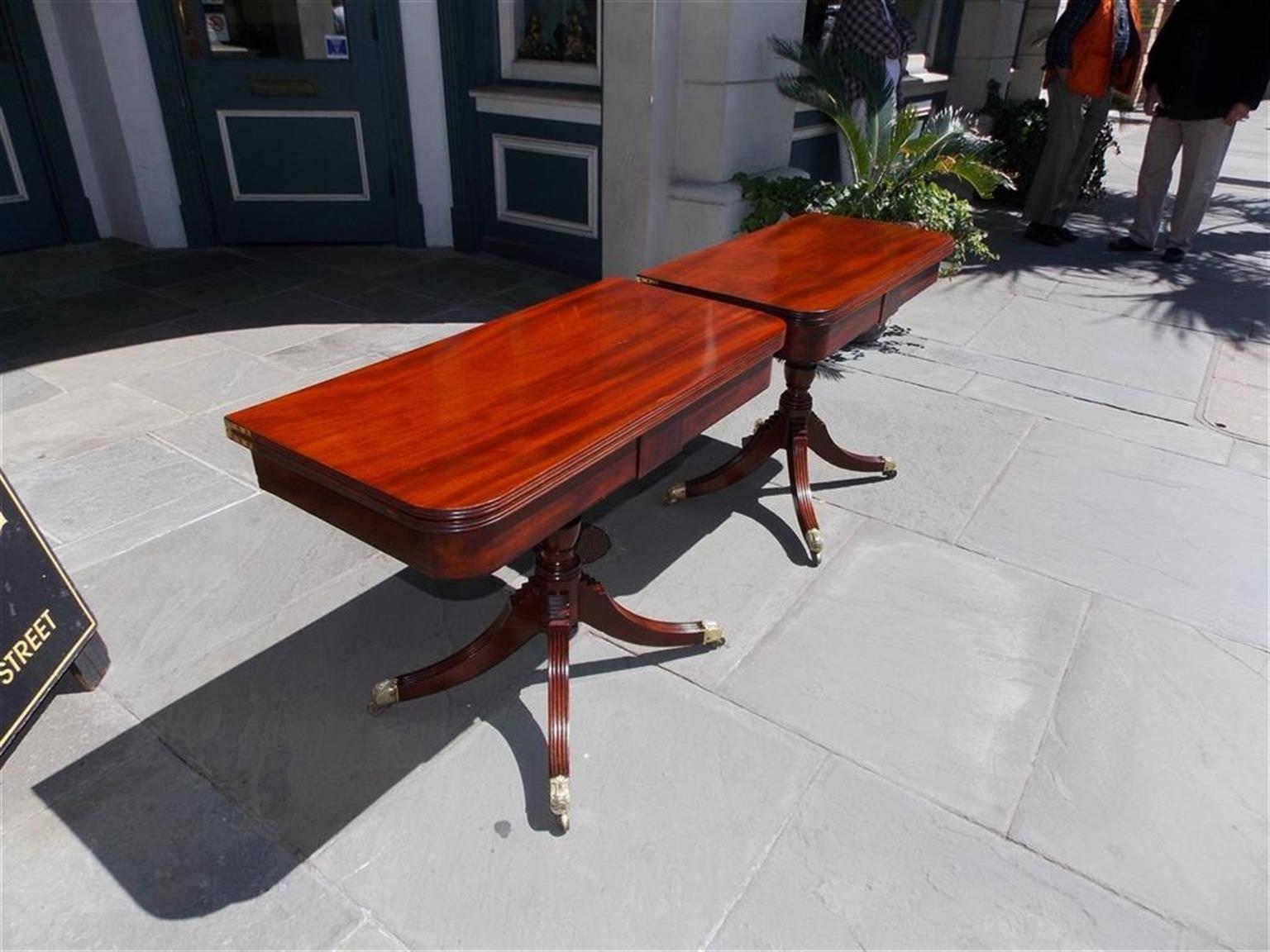 Pair of English Regency mahogany card tables with carved reeded molded edge, cross banded Kingwood skirt, turned bulbous ringed pedestal, and terminating on four step back reeded legs with the original floral shell brass casters, Early 19th