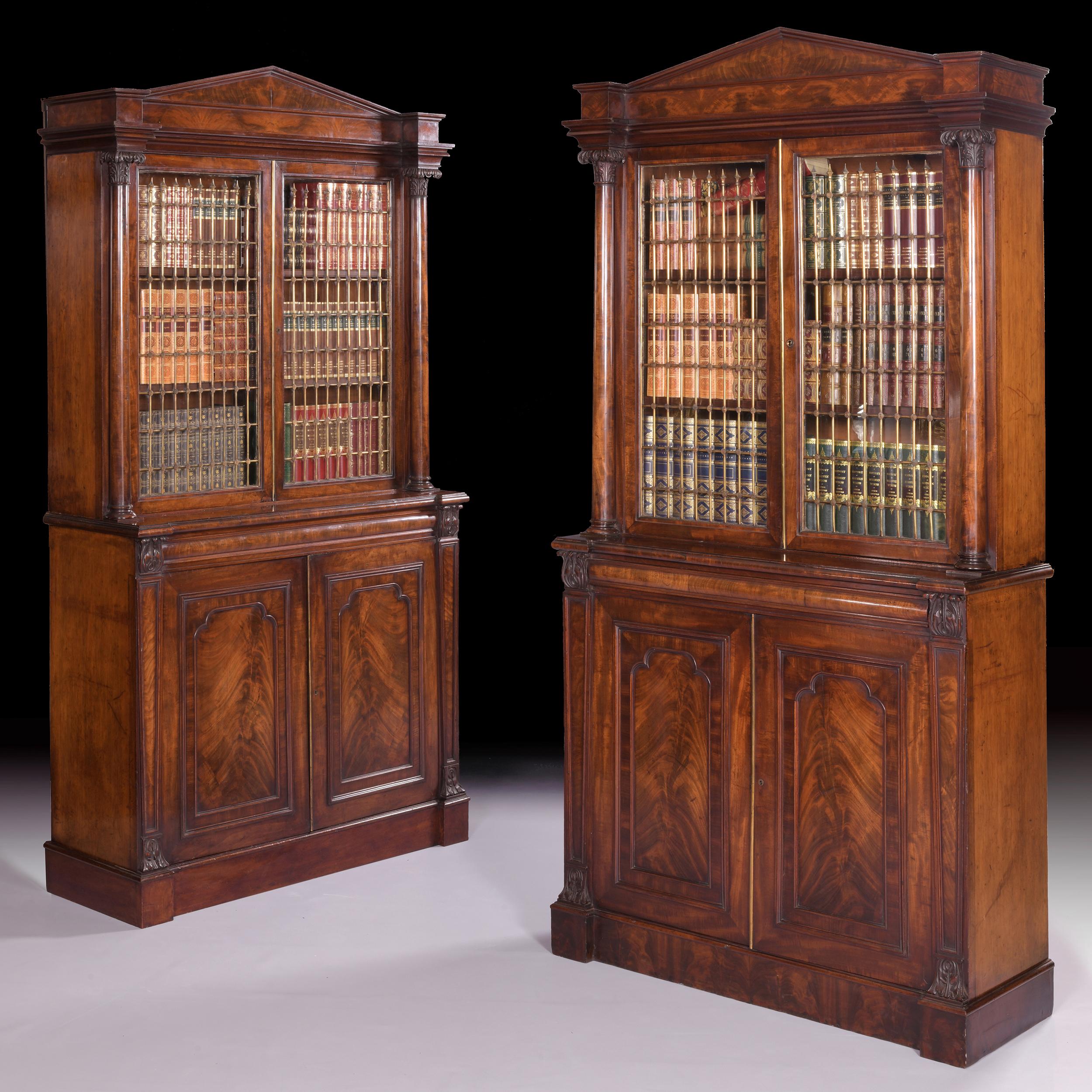 An exceptional pair of English Regency mahogany architectural bookcases by Gillows Of Lancaster.

The moulded architectural cornice above a pair of glazed and brass panelled doors flanked with lotus carved capitals, which open to reveal adjustable
