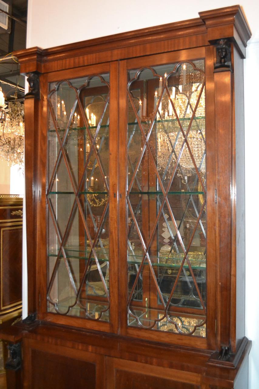 Superb pair of English Regency mahogany cabinets. Having carved ebonized caryatids, two glass doors with diamond-shape astragal mouldings, and a mirrored interior with glass shelves. Exhibiting a rich warm patina fantastic for many types of decor!