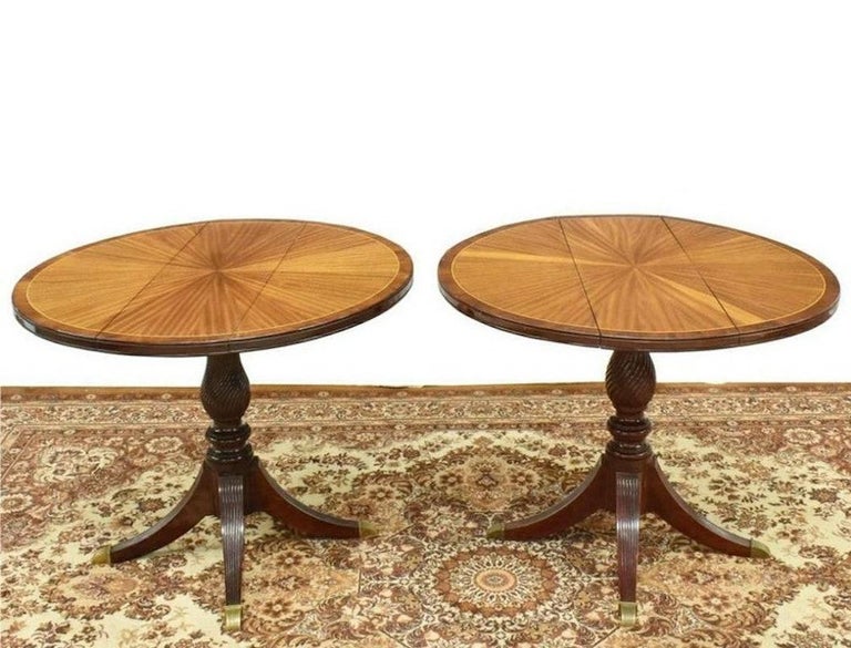 A pair of English Regency style mahogany drop-leaf tables, early 20th century, banded top with radiating matched marquetry, fluted baluster-form center pedestal, on four reeded legs, ending in brass capped feet.

These fabulous tables are as