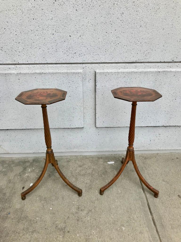An elegant pair of tilt-top red lacquer candle stands in the Regency style with octagonal tops and beautifully turned spiral pedestal bases supported by curving tripod legs resting on ball feet. These are handsome decorative elements that can serve