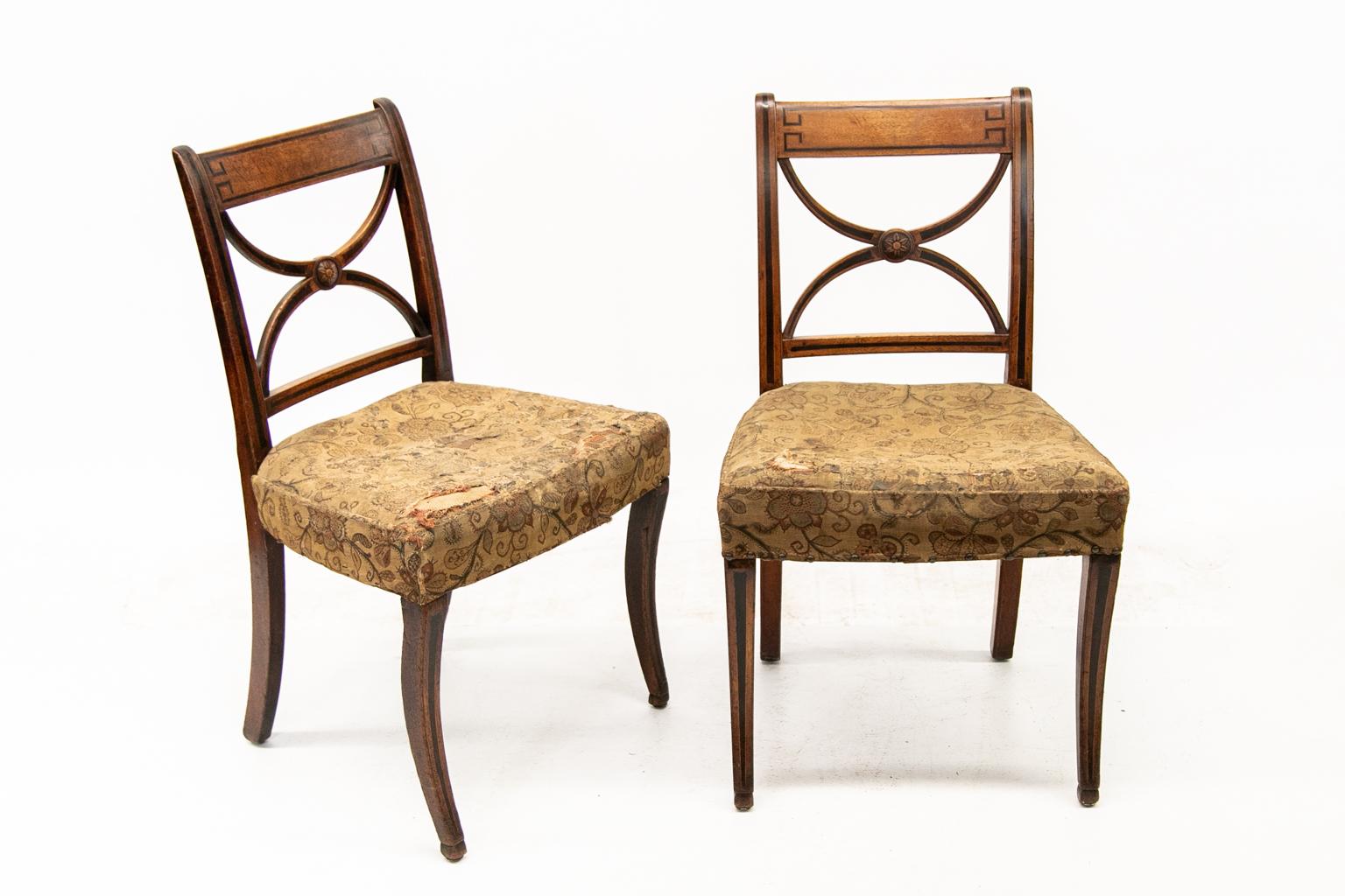 Pair of English Regency side chairs are made of mahogany and are inlaid with ebony line and boxwood inlay surrounding rosewood banding. The center of the splat has a carved floral medallion. There is a tapered rosewood inlay in the legs and
