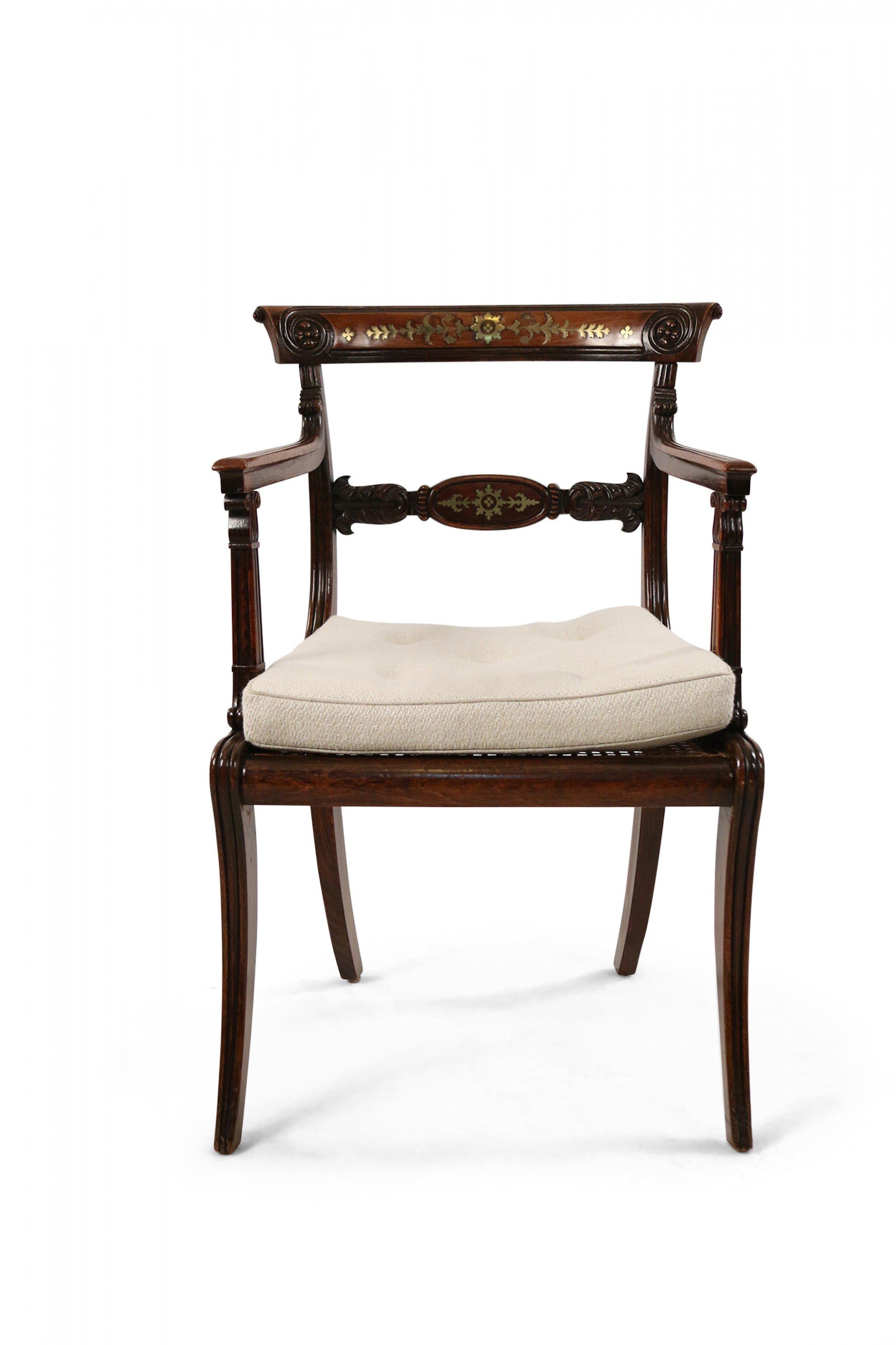 Pair of English Regency stained oak armchair with floral brass inlay pattern, carved detail, cane seat, and removable beige tufted and upholstered seat cushion.