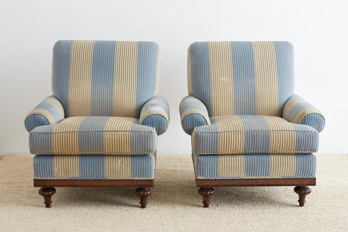 Grand pair of bespoke club chairs or lounge chairs produced by Kravet. Featuring a generous size frame made in the English Regency taste and upholstered in a whimsical velvet stripe pattern. Wide rolled arms and a thick cushion for ultimate comfort.