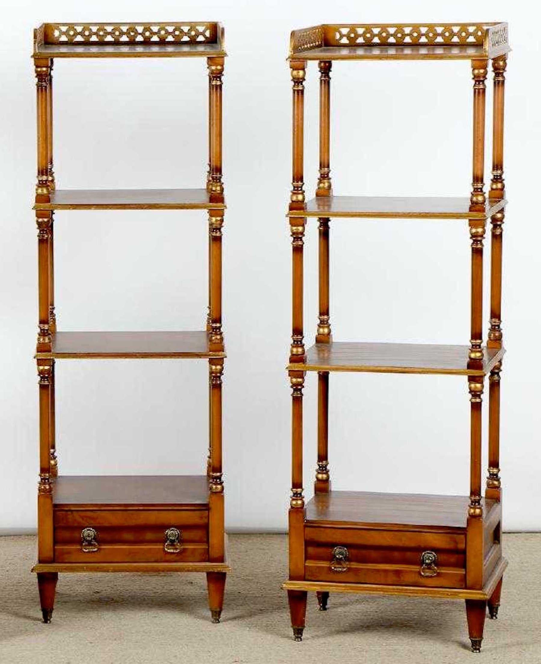 Pair of English Regency style mahogany and burl three tier étagerés, each one with pierced giltwood gallery, and one bottom drawer, with gilt highlights, raised on brass sabot legs.

 